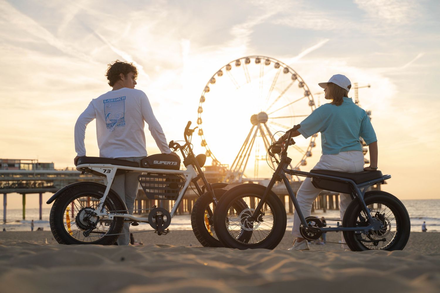 Silhouettes of custom motorcycles against a sunset backdrop with a ferris wheel.