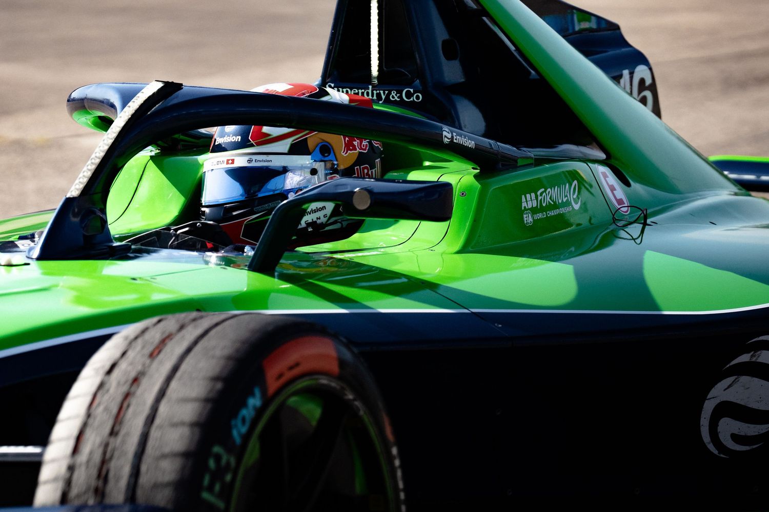Green Formula E race car with driver in cockpit, featuring Halo safety device, number 46, on track during competition.