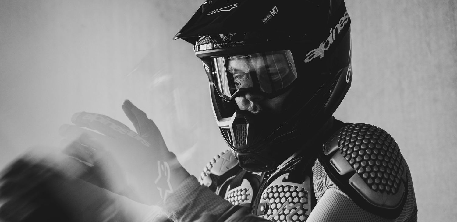 Black and white photo of a motocross rider wearing a helmet, goggles, and protective gear.