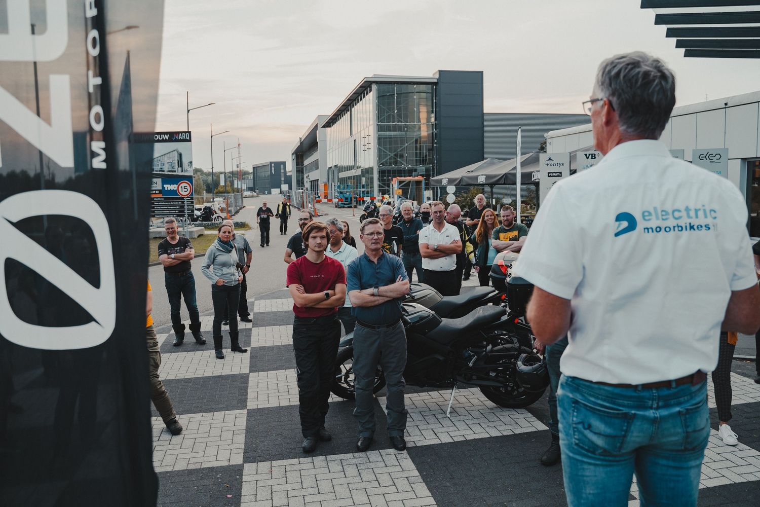 Outdoor gathering of motorcycle enthusiasts in an urban setting.