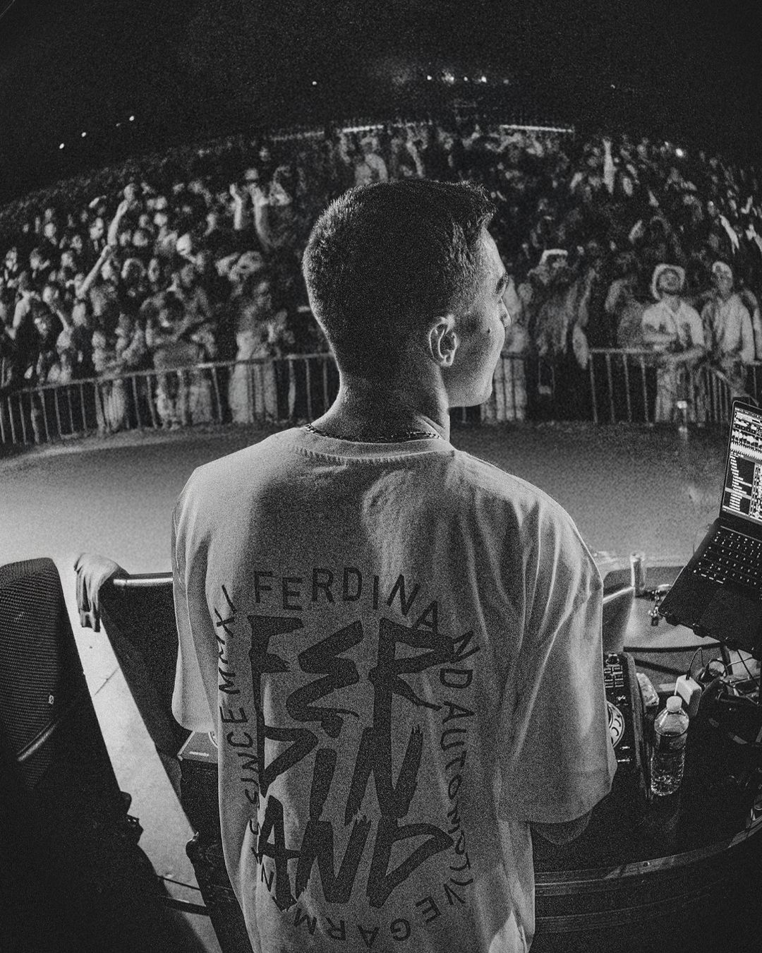 Black and white view of performers on stage from behind showing text on their shirts.