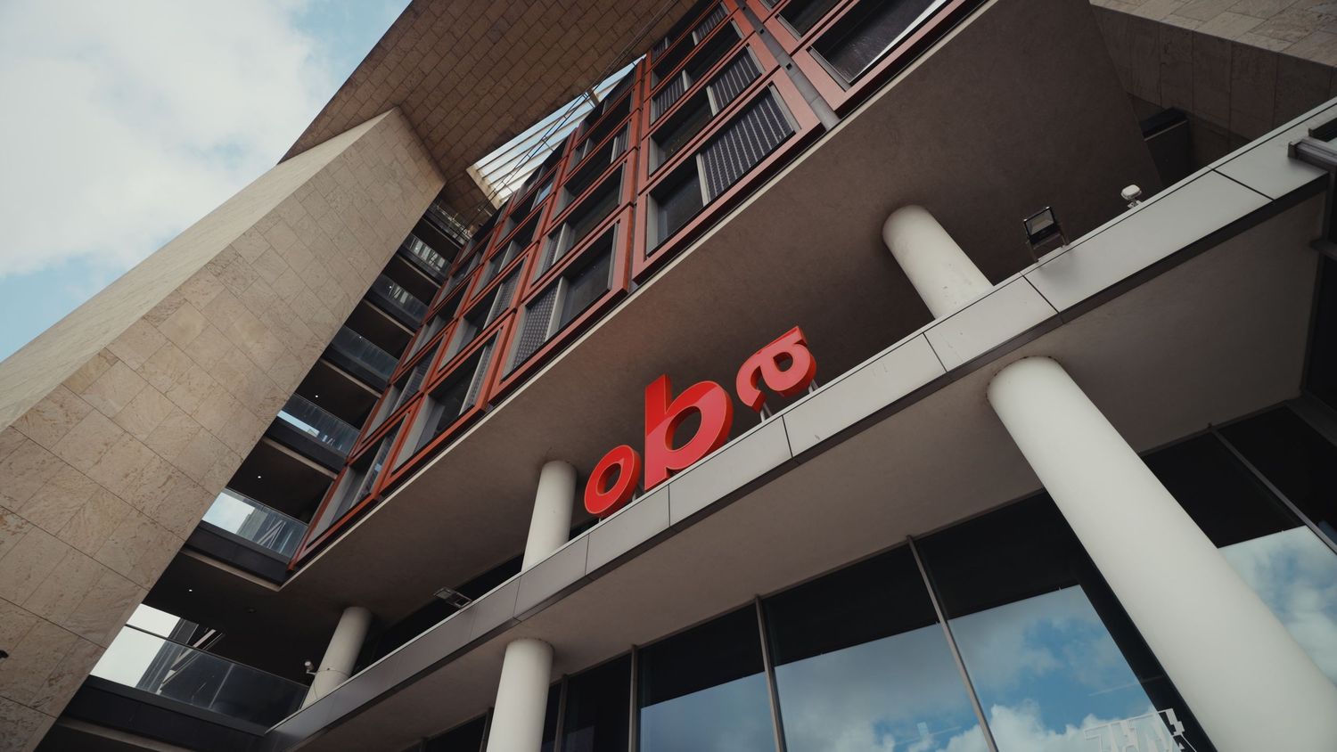 Modern building exterior featuring bold red OBR logo signage on a contemporary brick and glass facade.