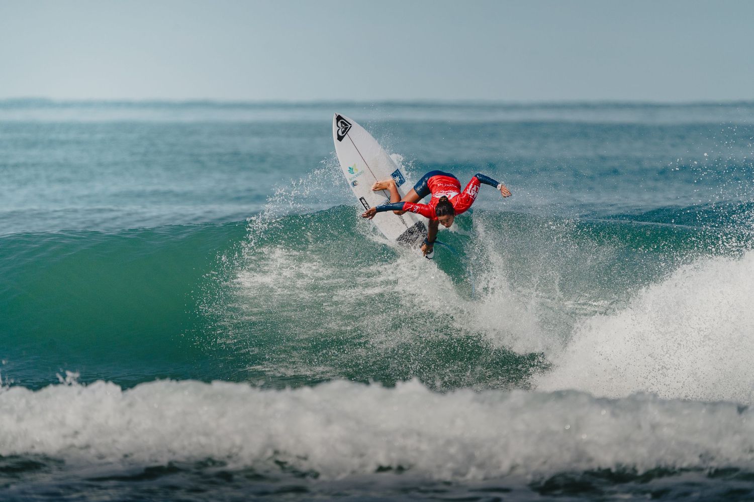 Surfer executing high-flying aerial tricks on turquoise ocean waves.