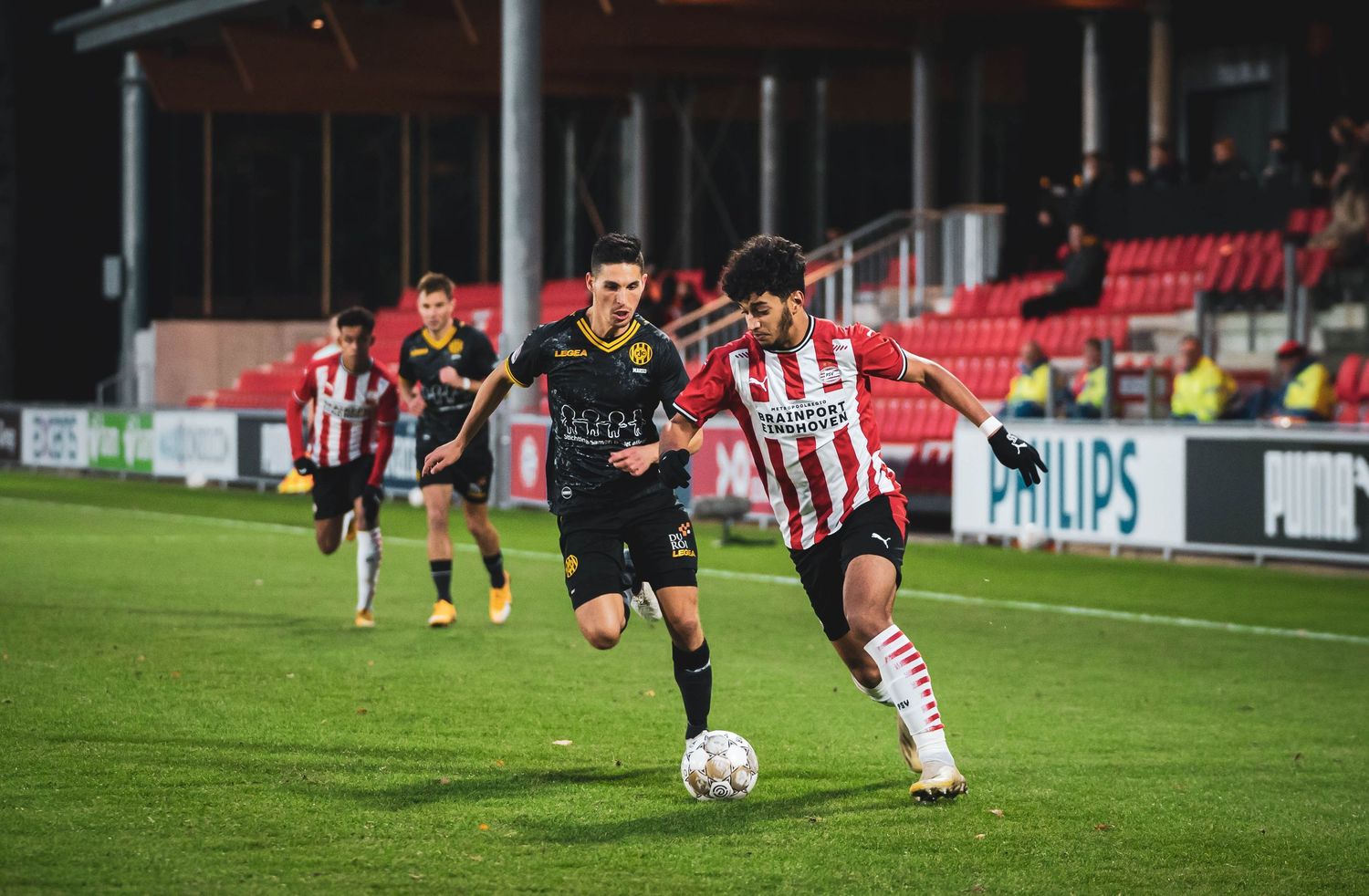 Wide angle view of a soccer match with players spread across the illuminated field.