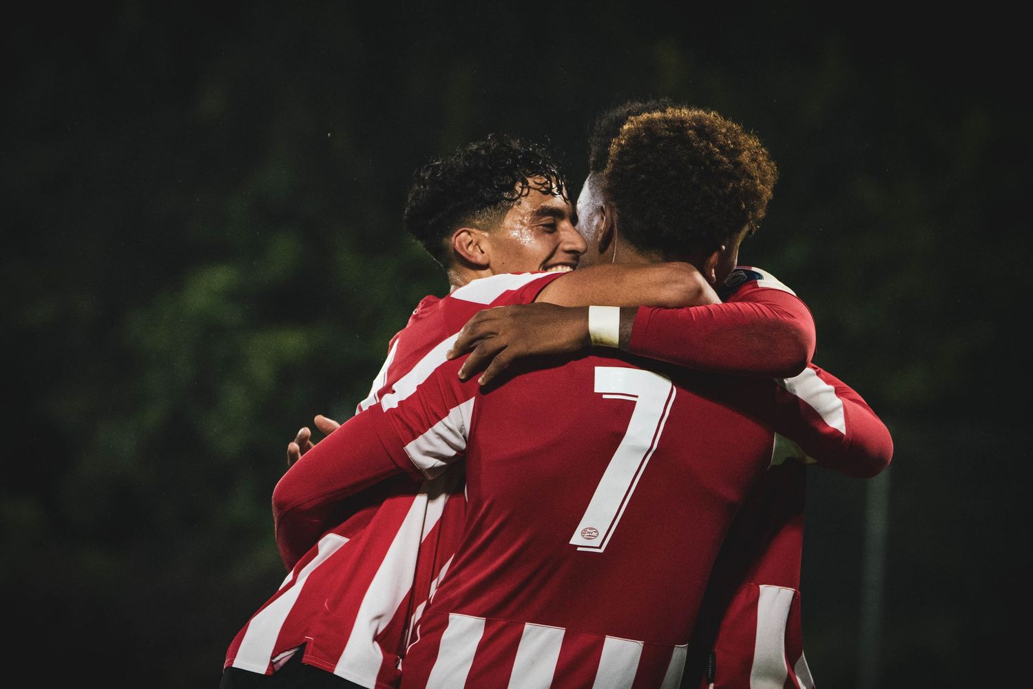 Players embrace in celebration wearing red and white striped uniforms.