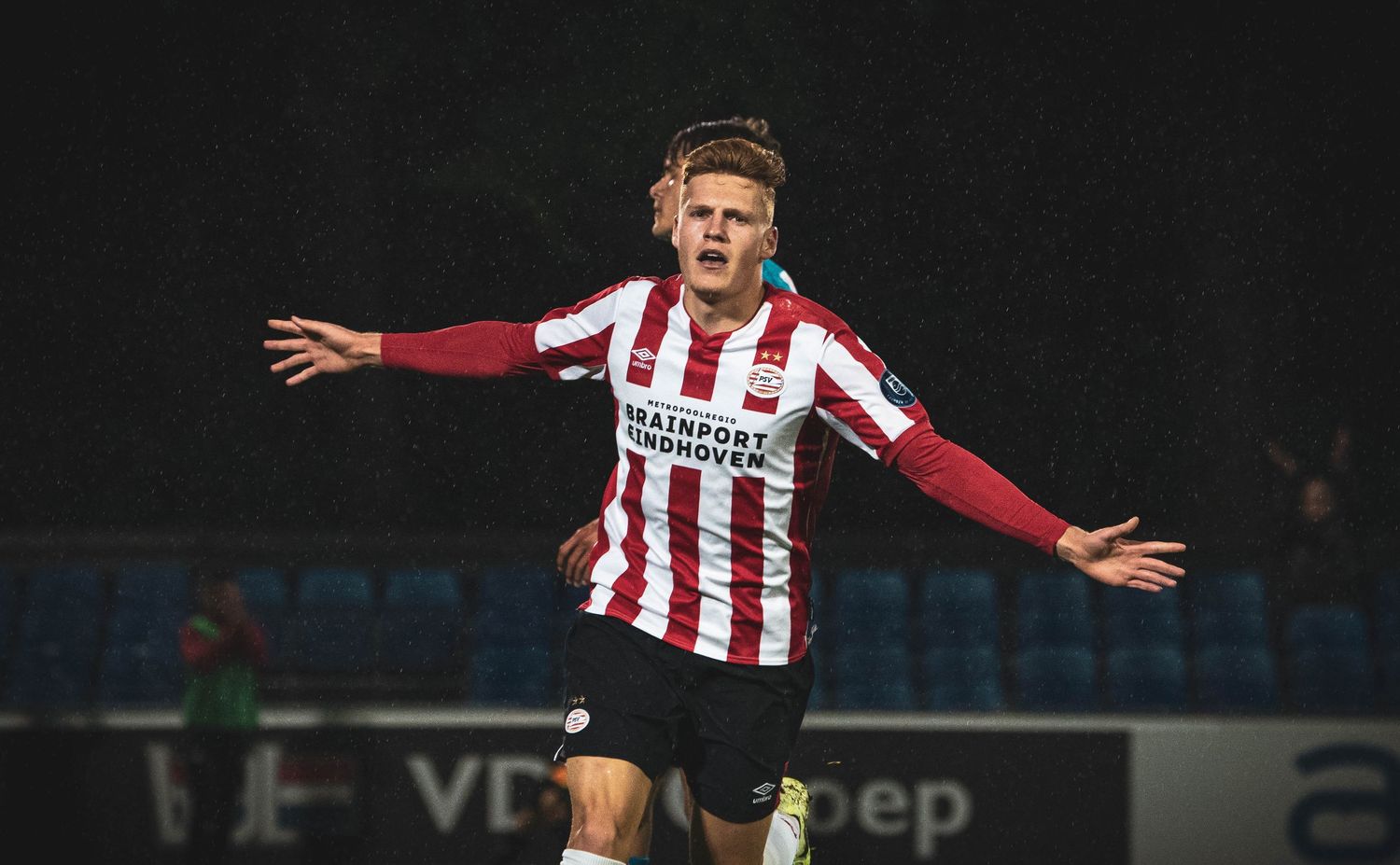 Soccer player in red and white stripes celebrates with arms outstretched.