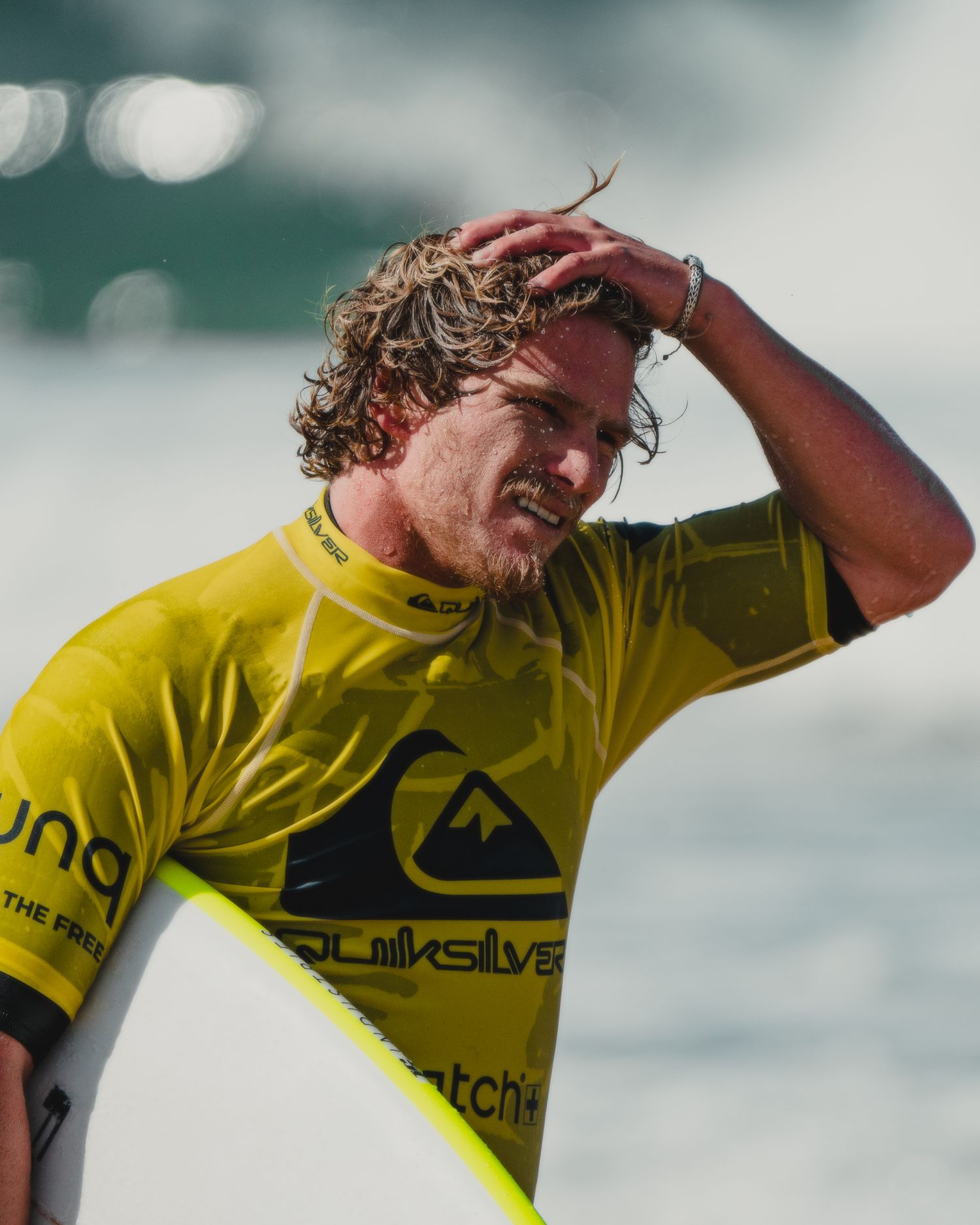Surfer in yellow competition jersey celebrating during a surfing event.