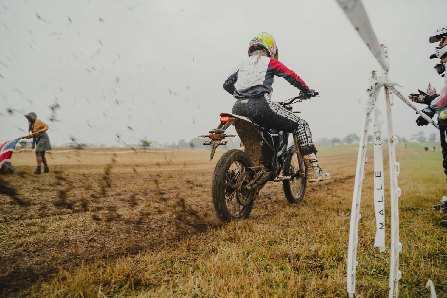 Motorcycle rider jumping over dirt track during an off-road racing competition.
