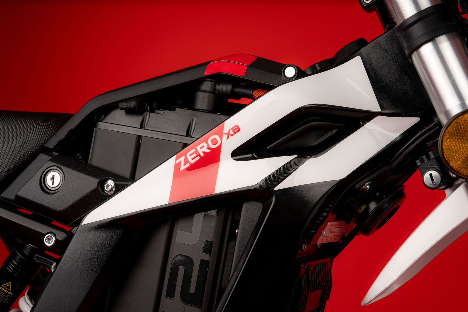 White and red motorcycle parts detail showing sleek bodywork against red backdrop.