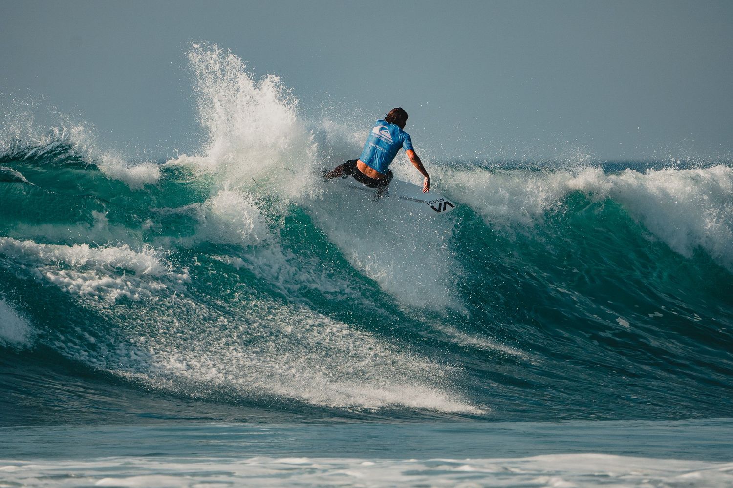 A surfer carves along the face of a powerful ocean wave.