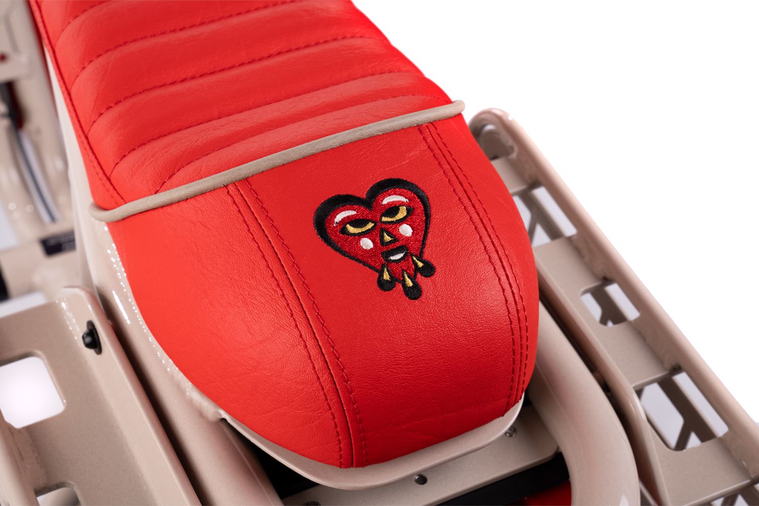 Detailed view of red leather motorcycle seat cushioning and logo pattern.