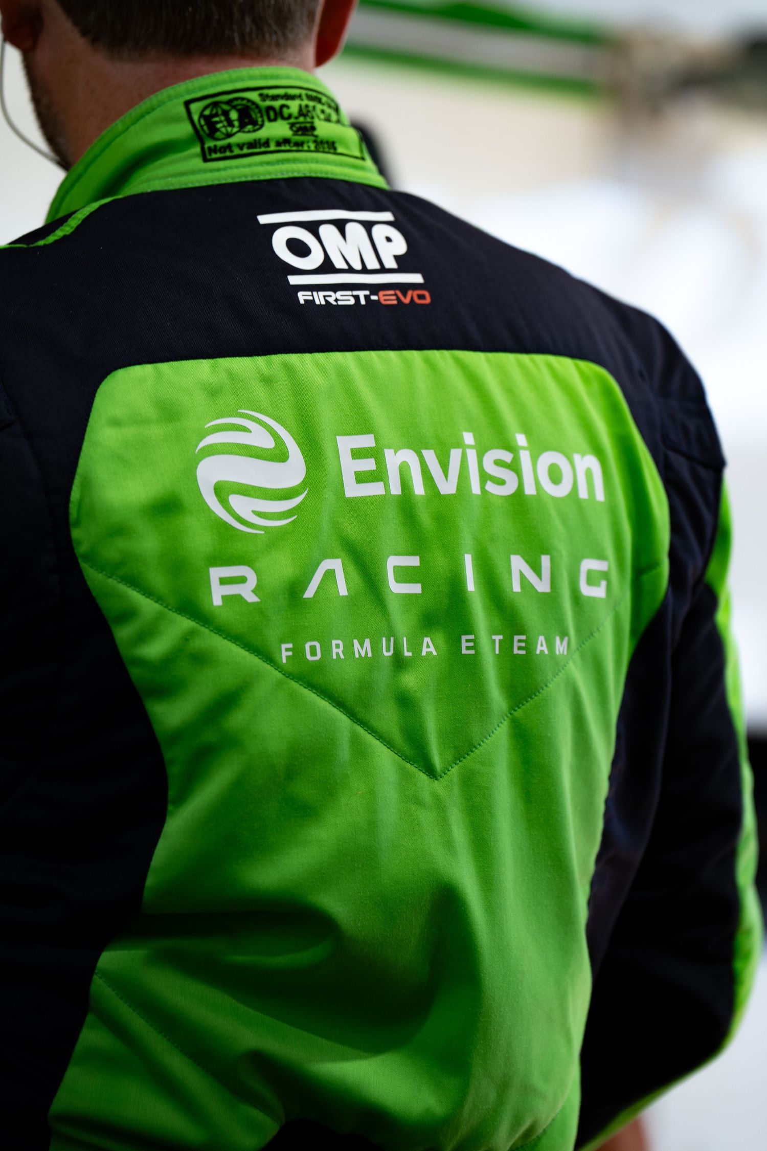 Close-up of an Envision Racing Formula E Team jacket with OMP First-Evo branding in green and black.