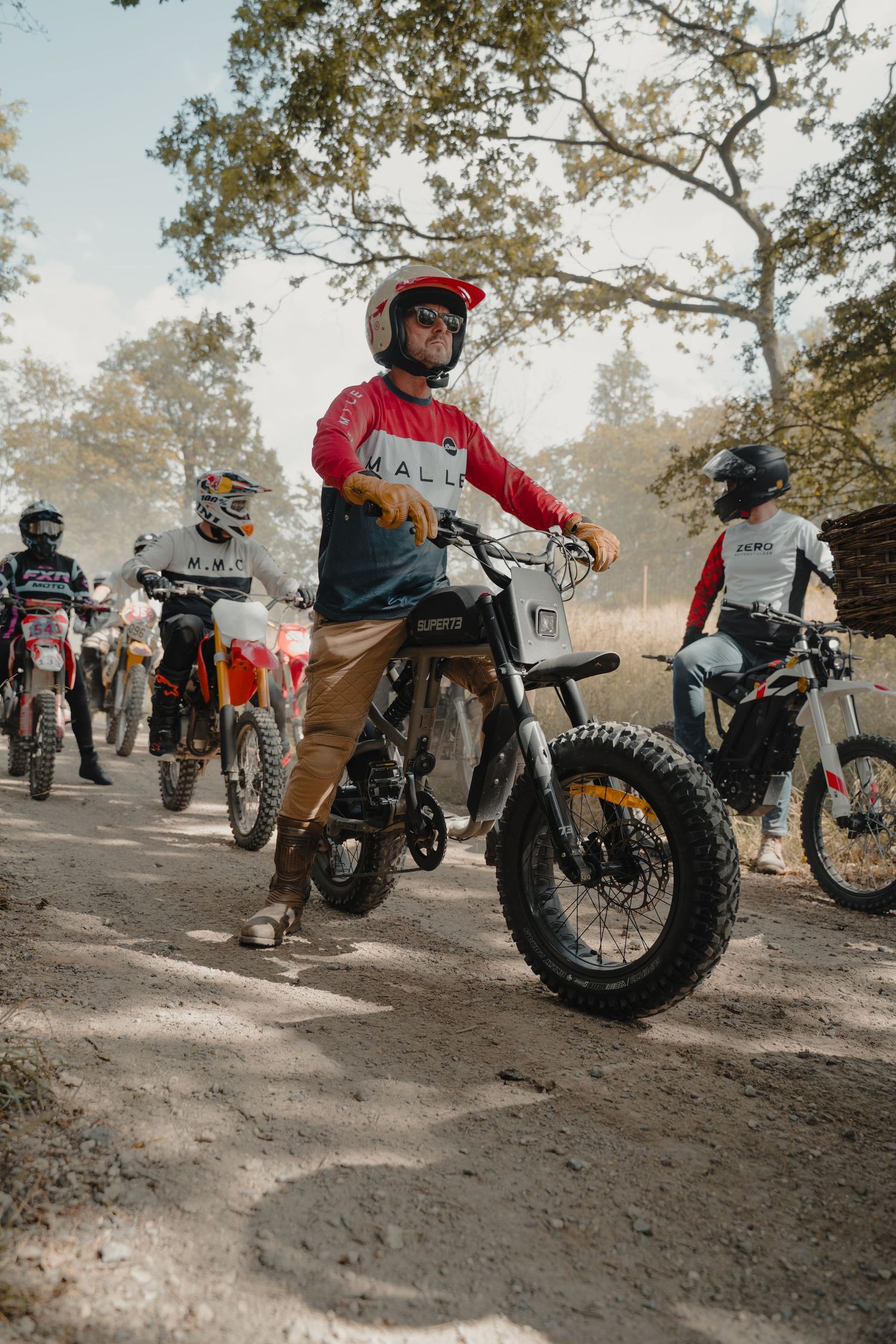 Group of dirt bike riders gathered on a forest trail.