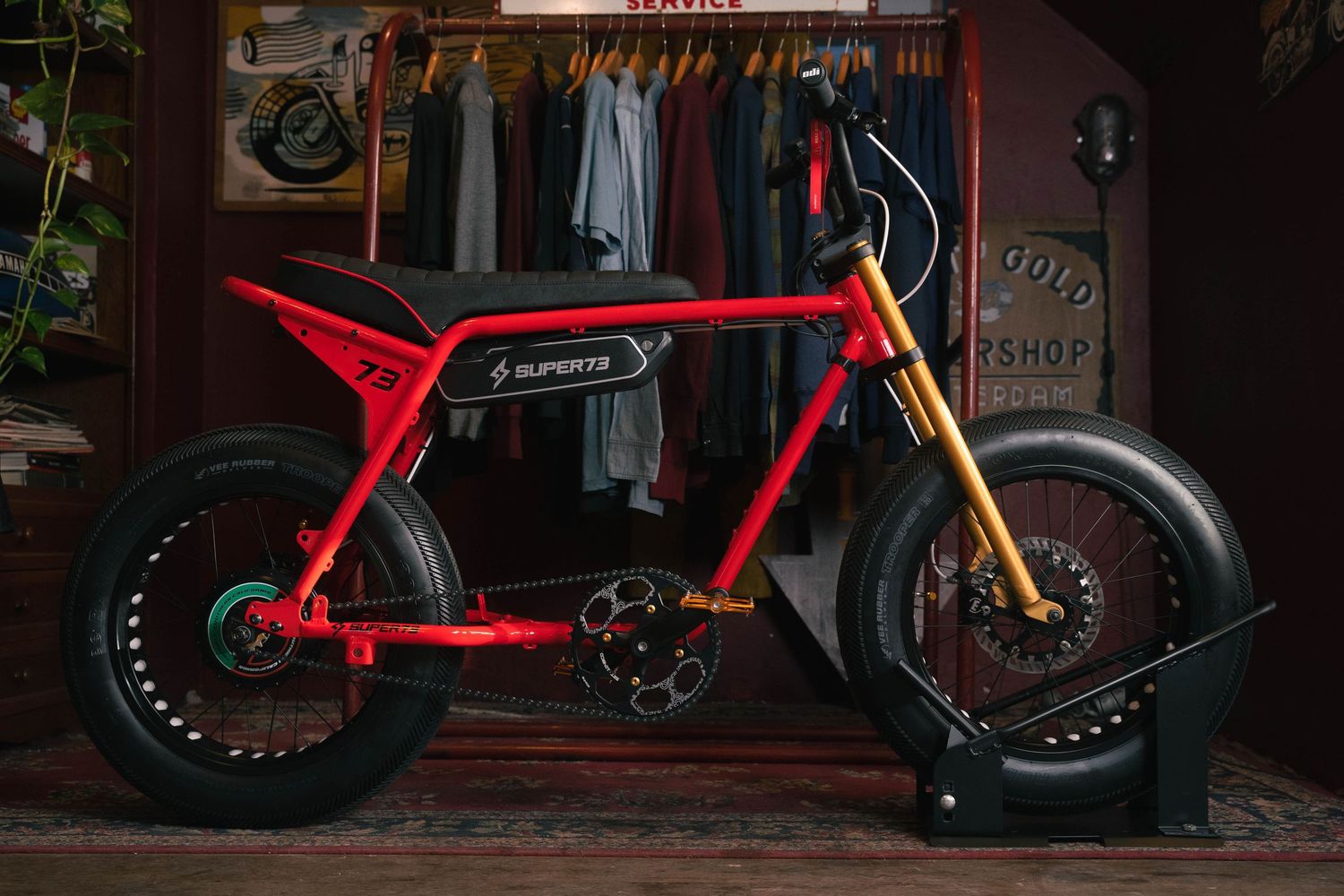 Bright red electric minibike with gold front forks and fat tires in urban setting.