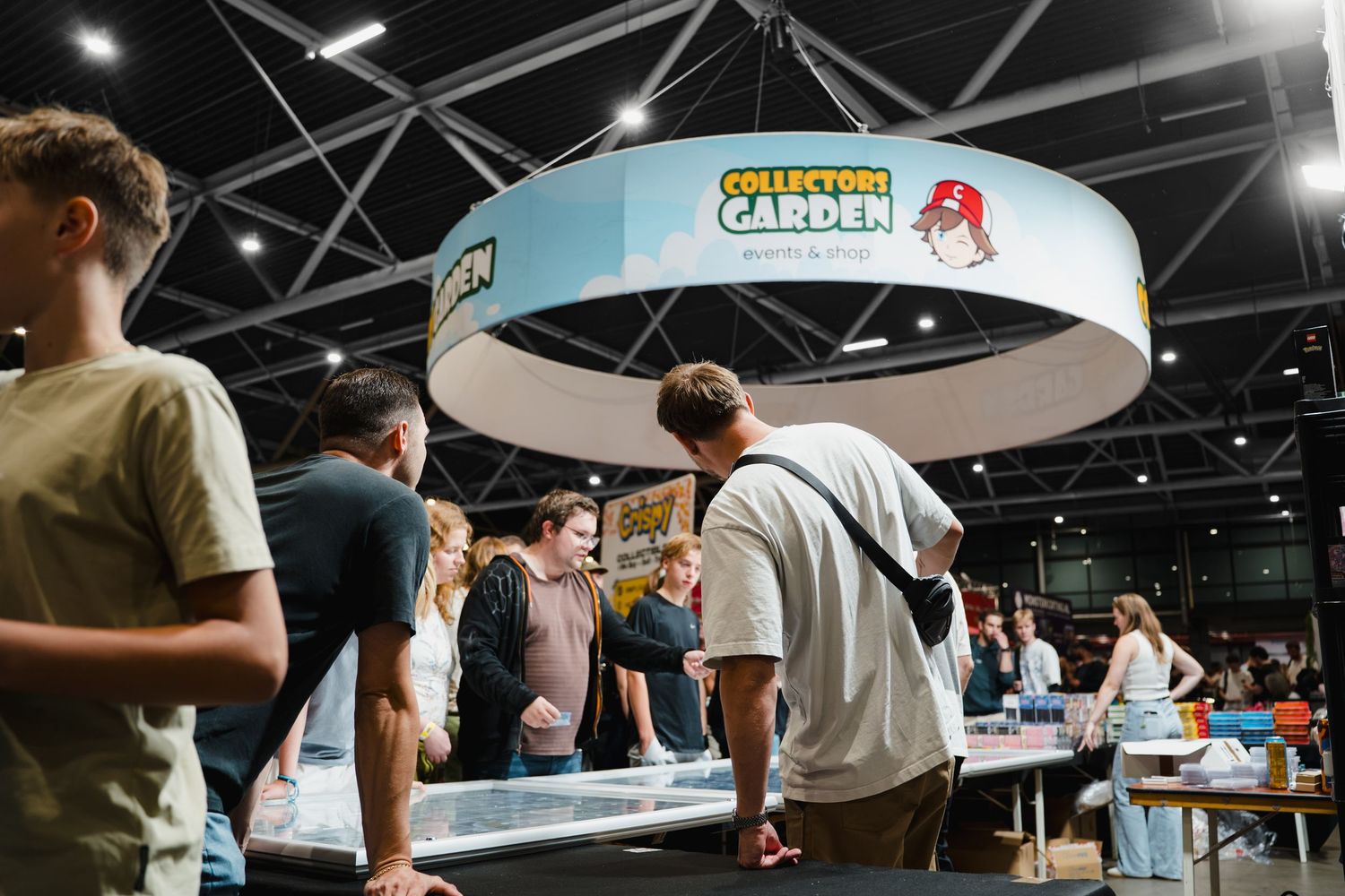 Visitors browse displays at the Collectors Garden booth inside a modern exhibition hall during a busy trade show event.