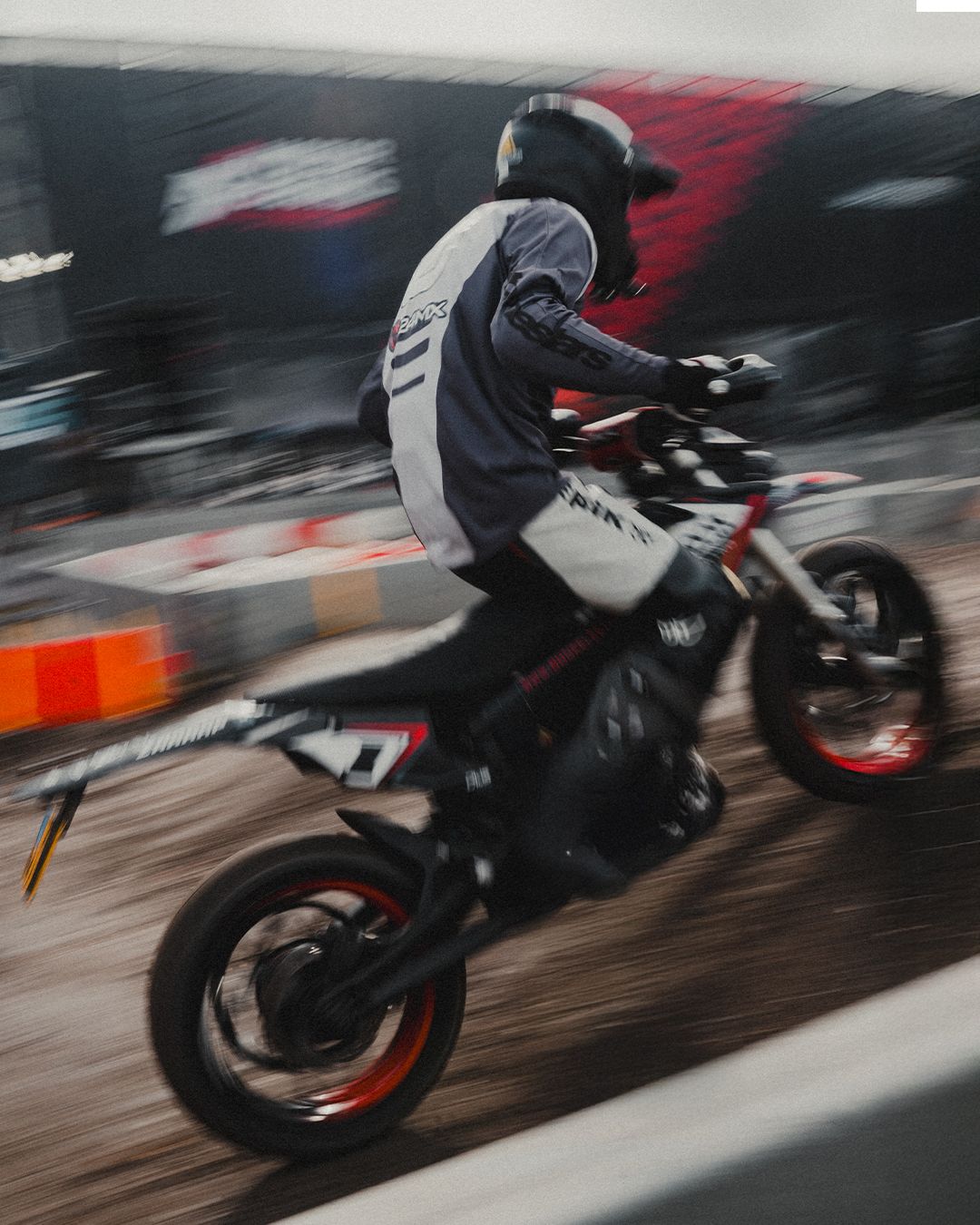 Motion-blurred shot of a motorcycle rider performing a stunt on a dirt track.