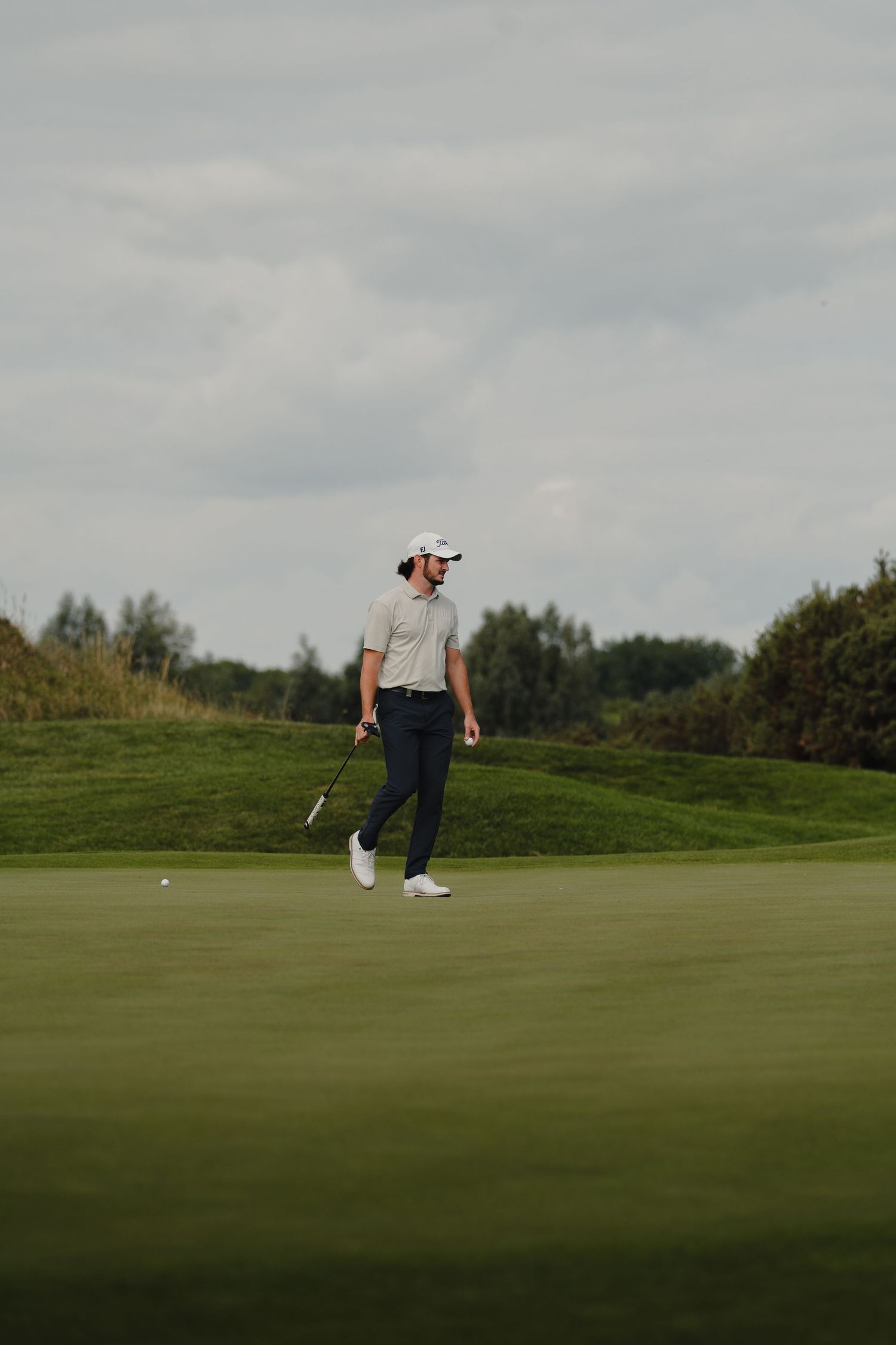 Wide angle view of a golf green with players visible in the distance.
