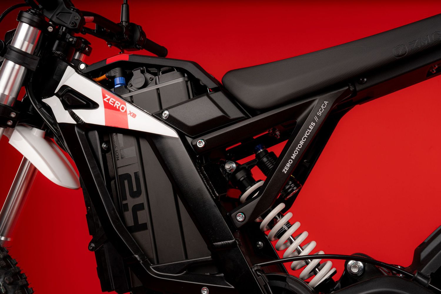 Close-up of white and black motorcycle body panels with angular design on red background.