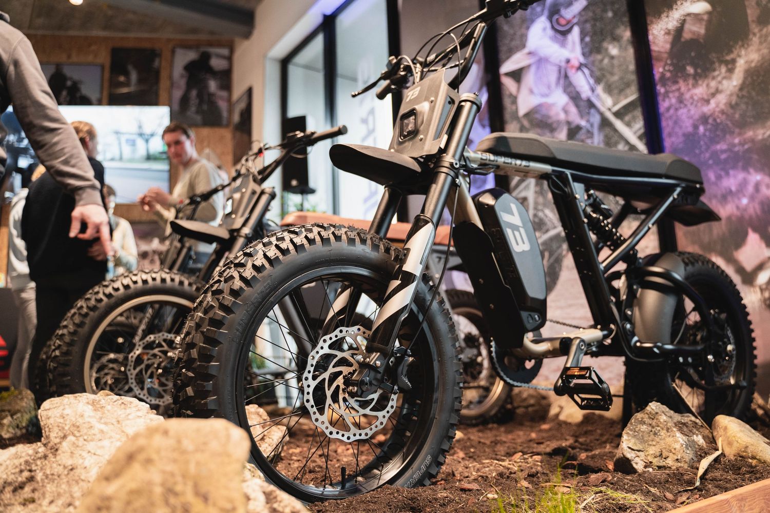 Close-up of rugged off-road motorcycle tires and suspension on display with rocks.