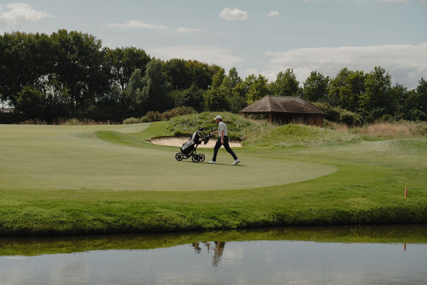 Panoramic view of a pristine golf course with water hazard and lush green fairways.