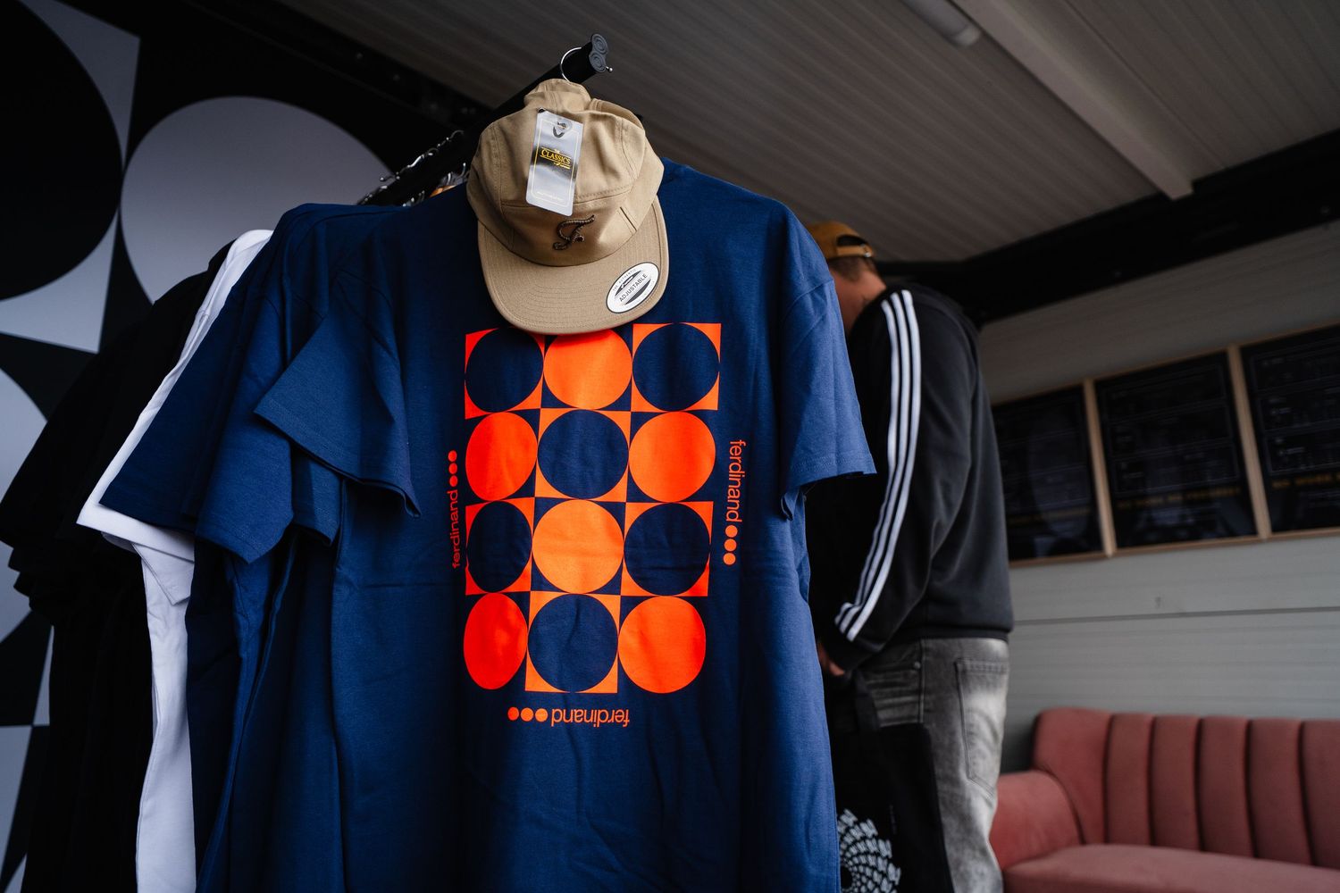 Navy blue t-shirt with orange circle graphic design displayed on hanger in retail shop.