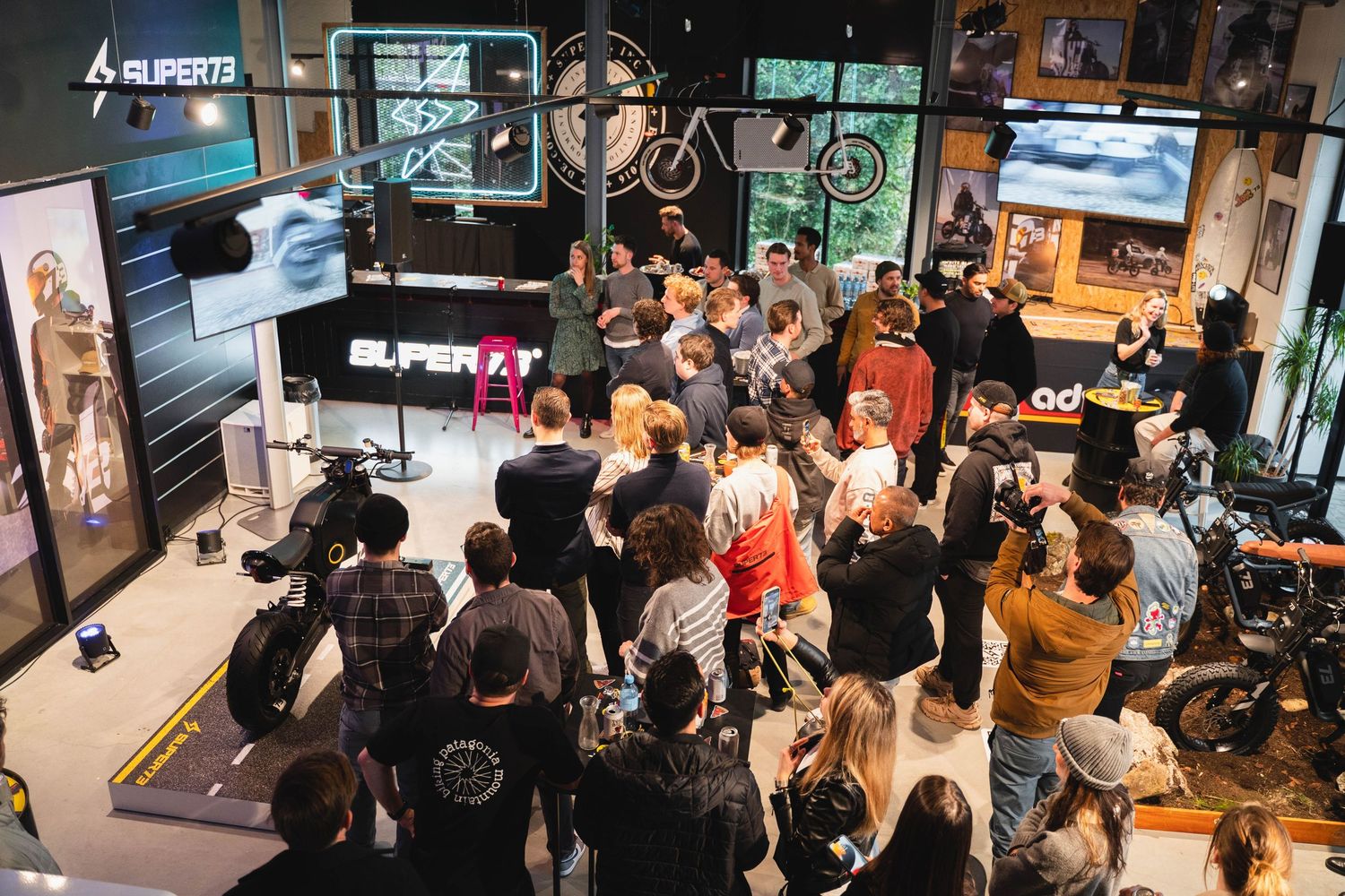 Busy motorcycle showroom event with displays and crowd gathering around exhibits.