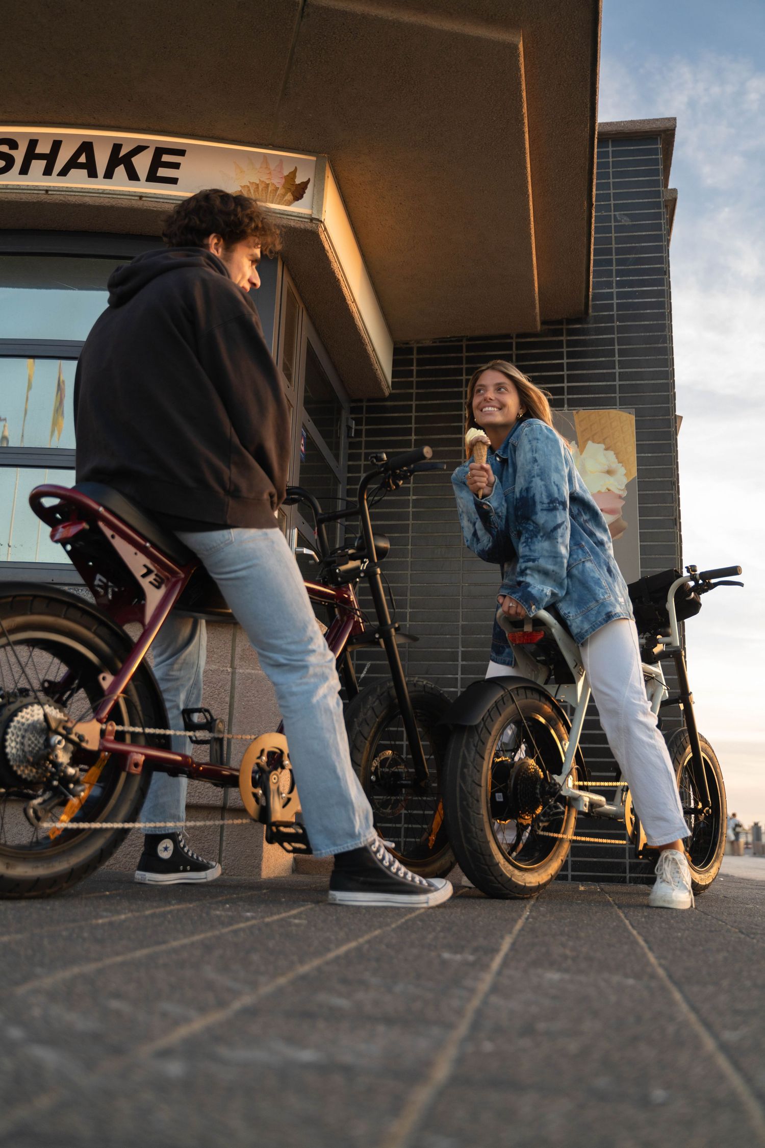 Low-angle shots of people with custom bikes outside a Shake shop.