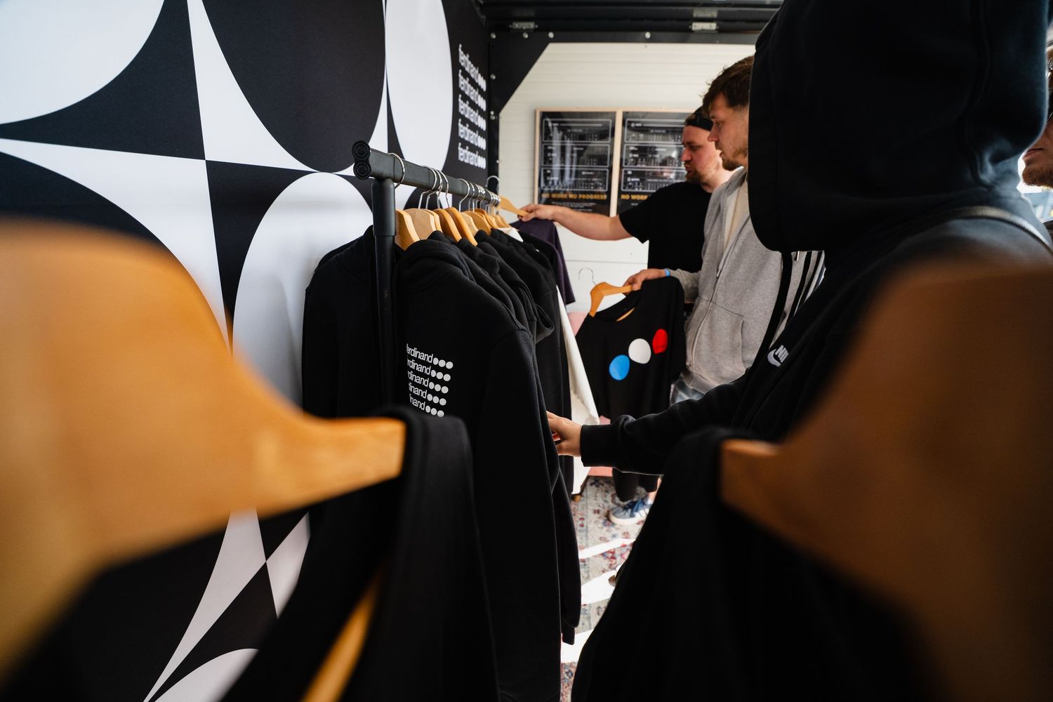 Person browsing black graphic t-shirts on a clothing rack in a modern retail store with bold black and white decor.