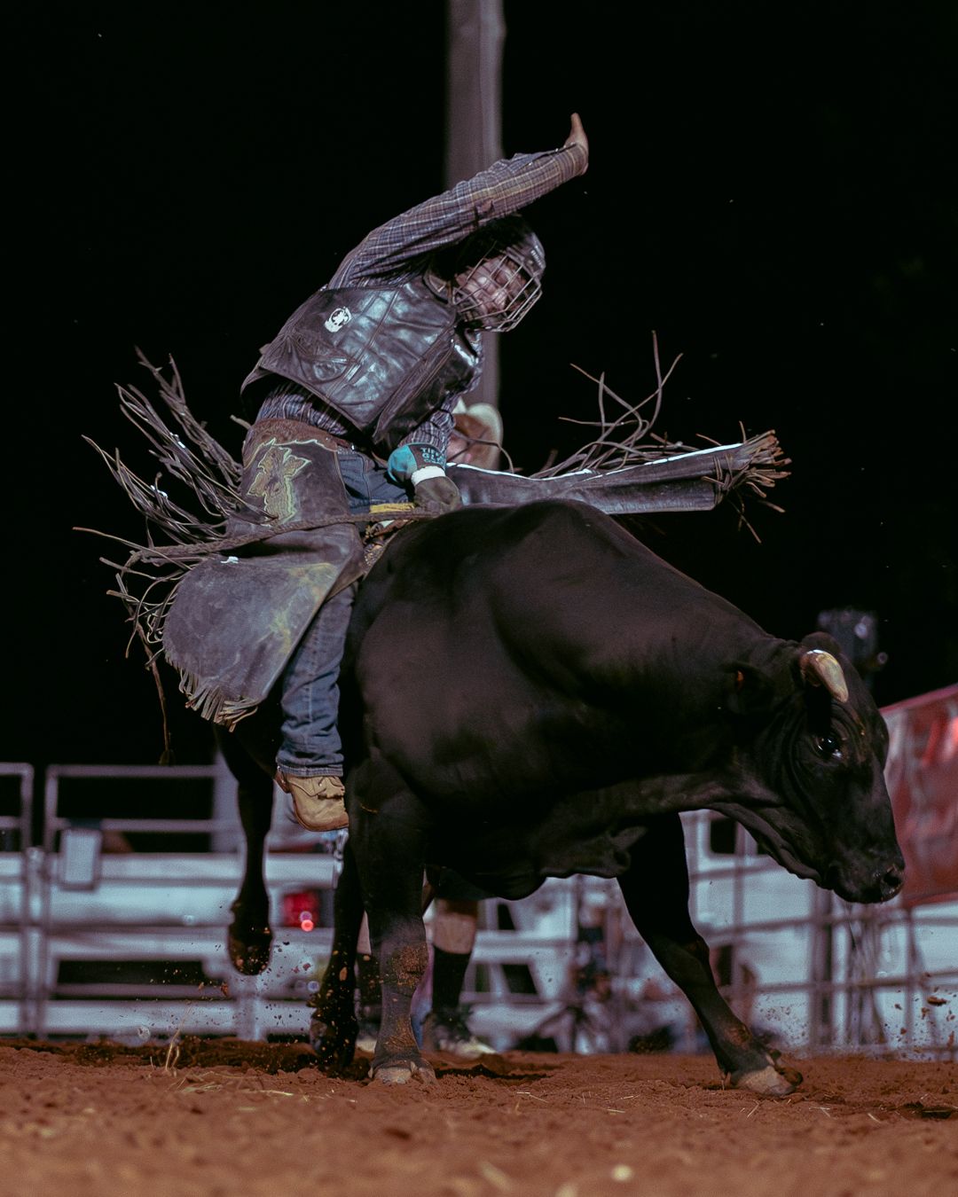 A cowboy on a bull starting to fall off.