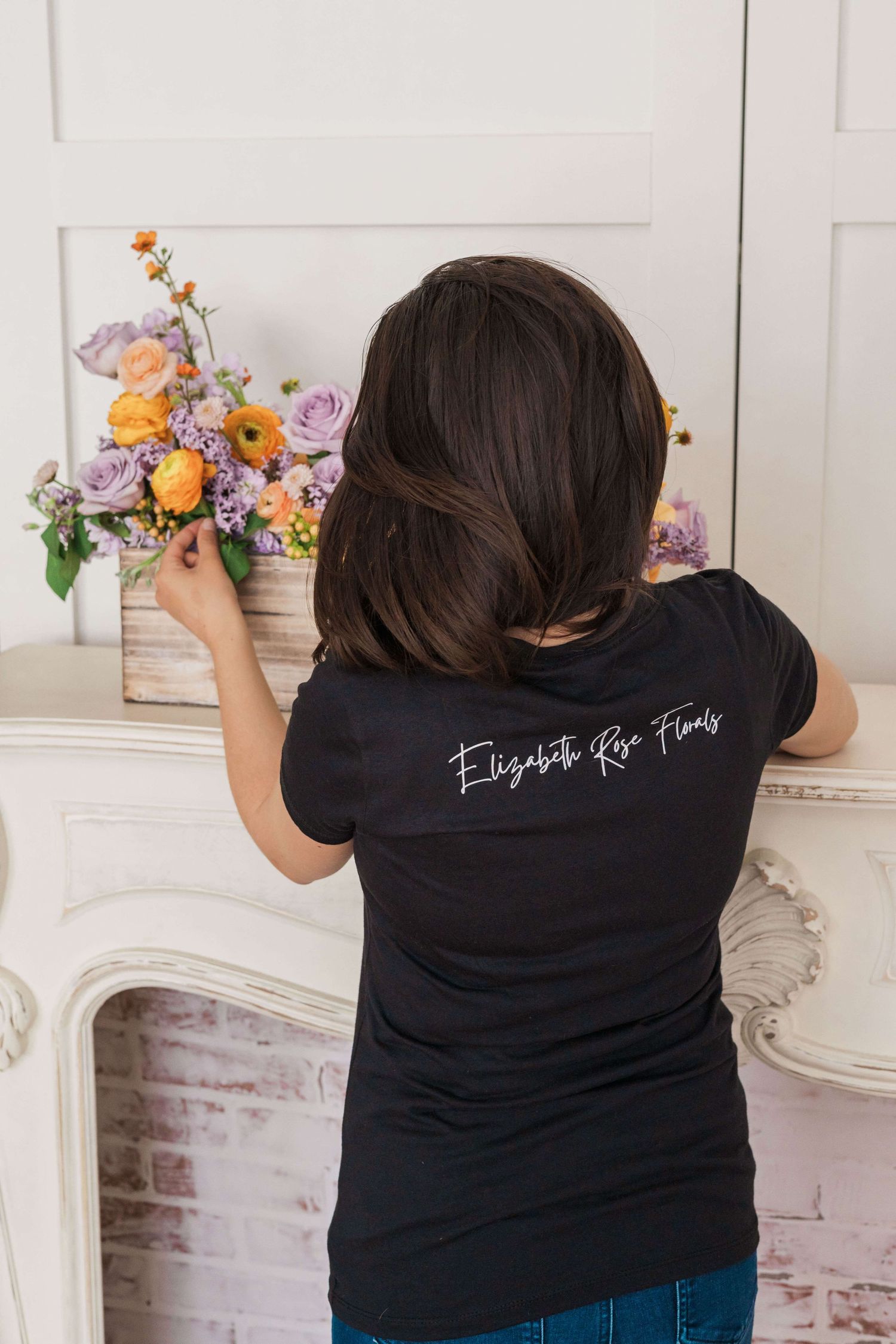 Elizabeth facing away while adjusting planter box arrangement wearing Elizabeth Rose Florals Black shirt