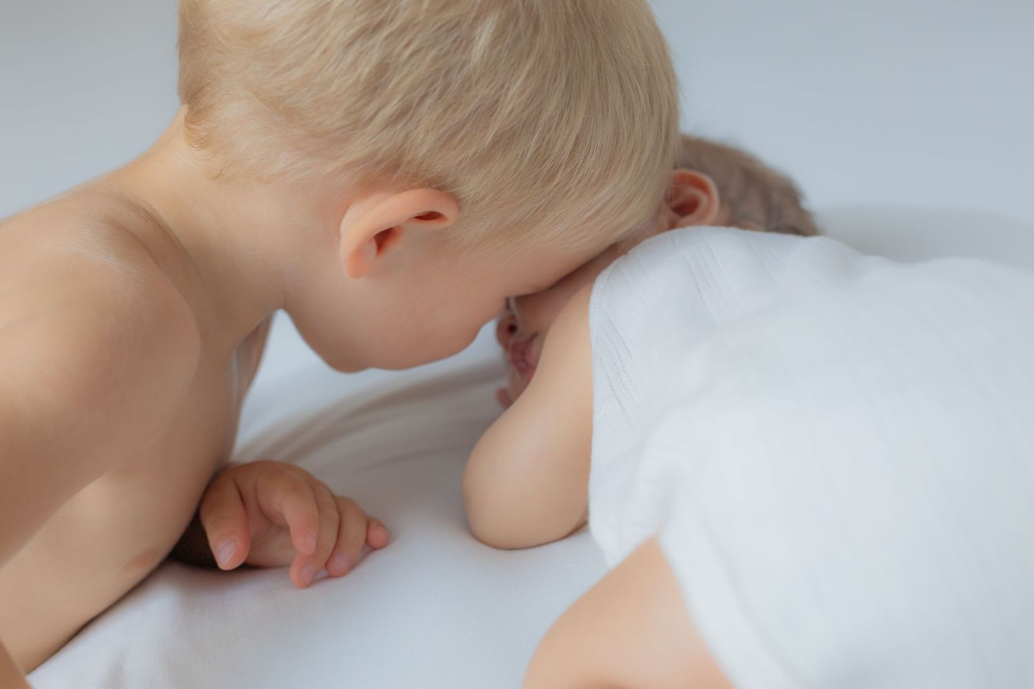 Hermano mayor dando un beso a su bebé recién nacido durante sesión newborn en Valdemoro, zona sur de Madrid. Fotografía tierna y natural.