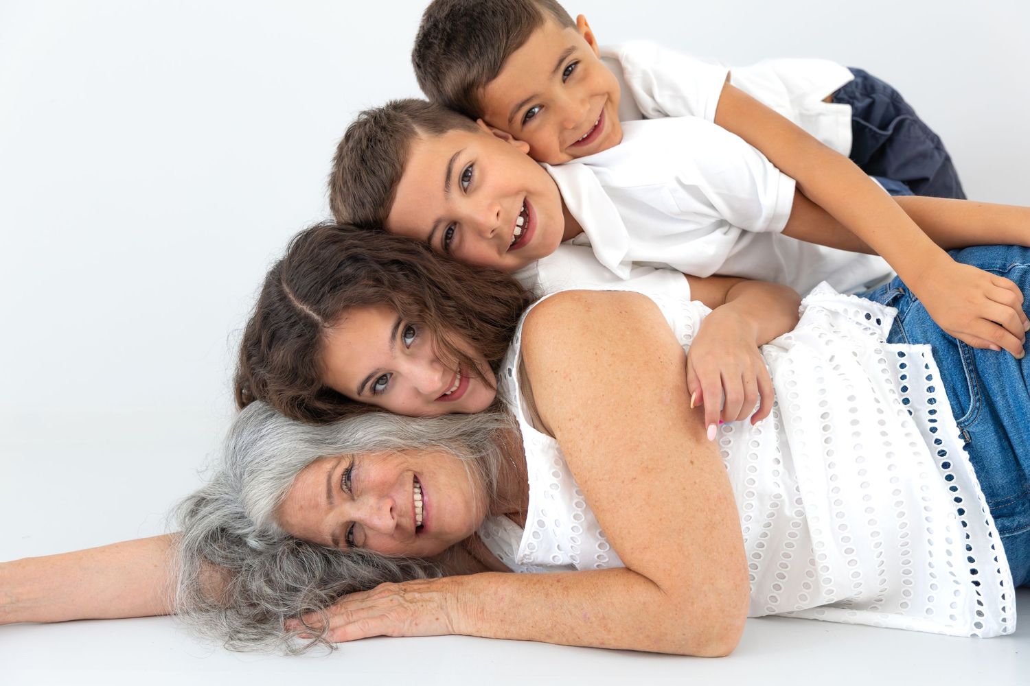 Abuela abrazada por sus nietos en una sesión familiar. Estudio en Valdemoro, zona sur de Madrid. Fotografía natural e intergeneracional.