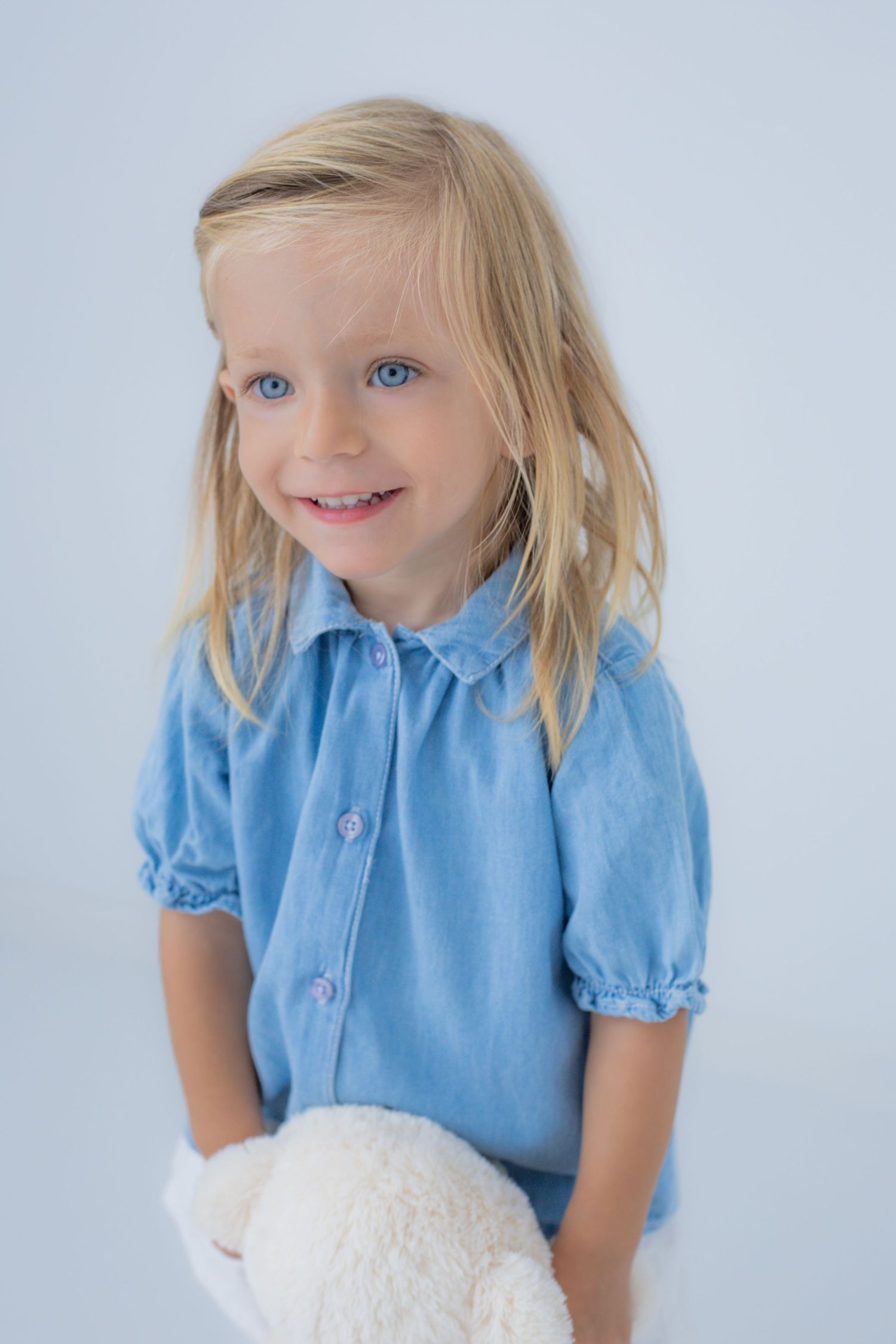 Retrato infantil de niña con camisa azul y osito de peluche en sesión familiar en Valdemoro, zona sur de Madrid. Fotografía emocional