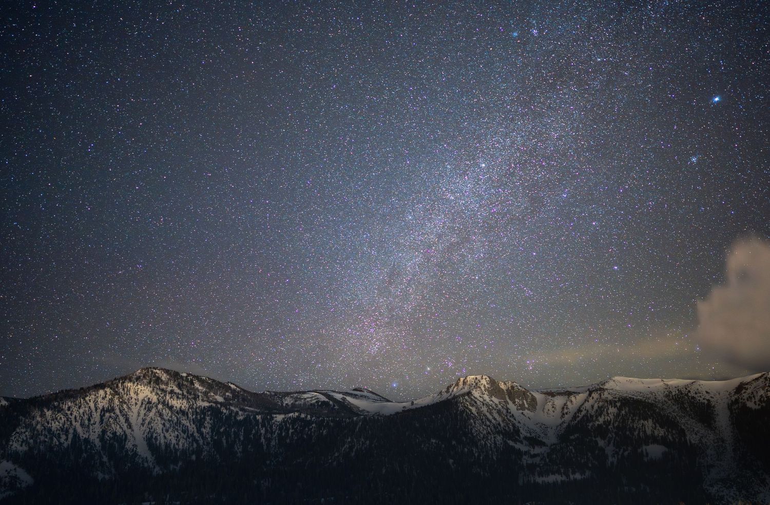 Dramatic wide-angle nature photograph of majestic mountains and stars under a moody sky by Vince Shewmaker.
