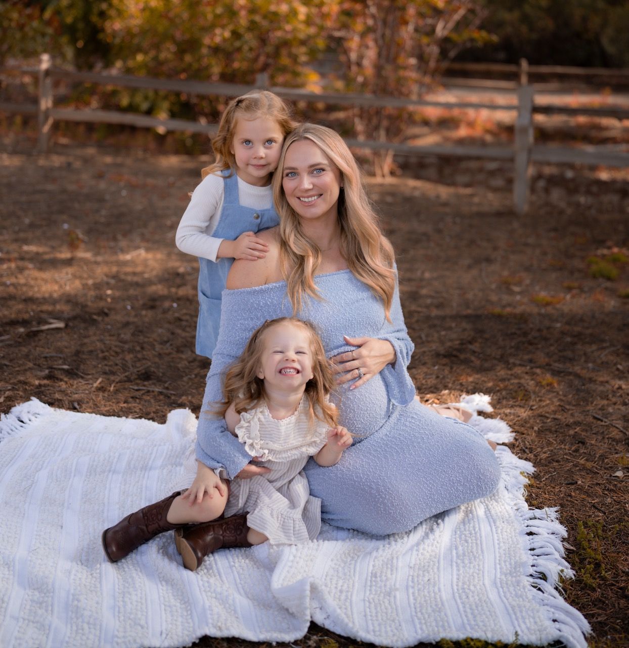 Mother and daughters relaxing together on a white blanket in an autumn forest setting in Redlands, California