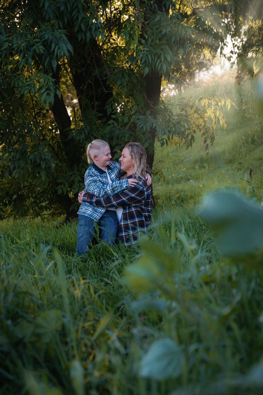 Romantic couple sharing intimate moments in tall grass during sunset.