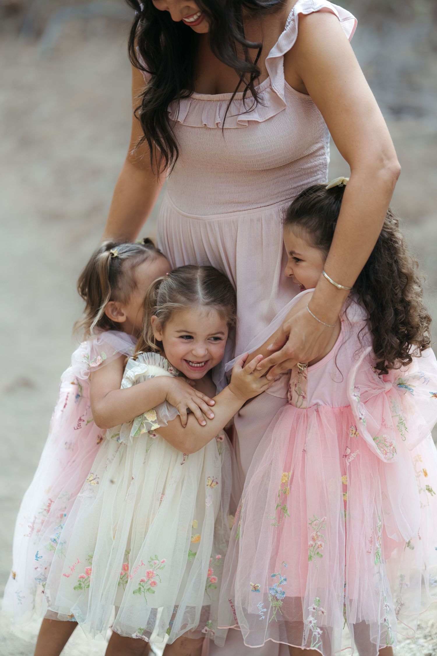 Sweet candid moment between parent and children wearing matching floral dresses.