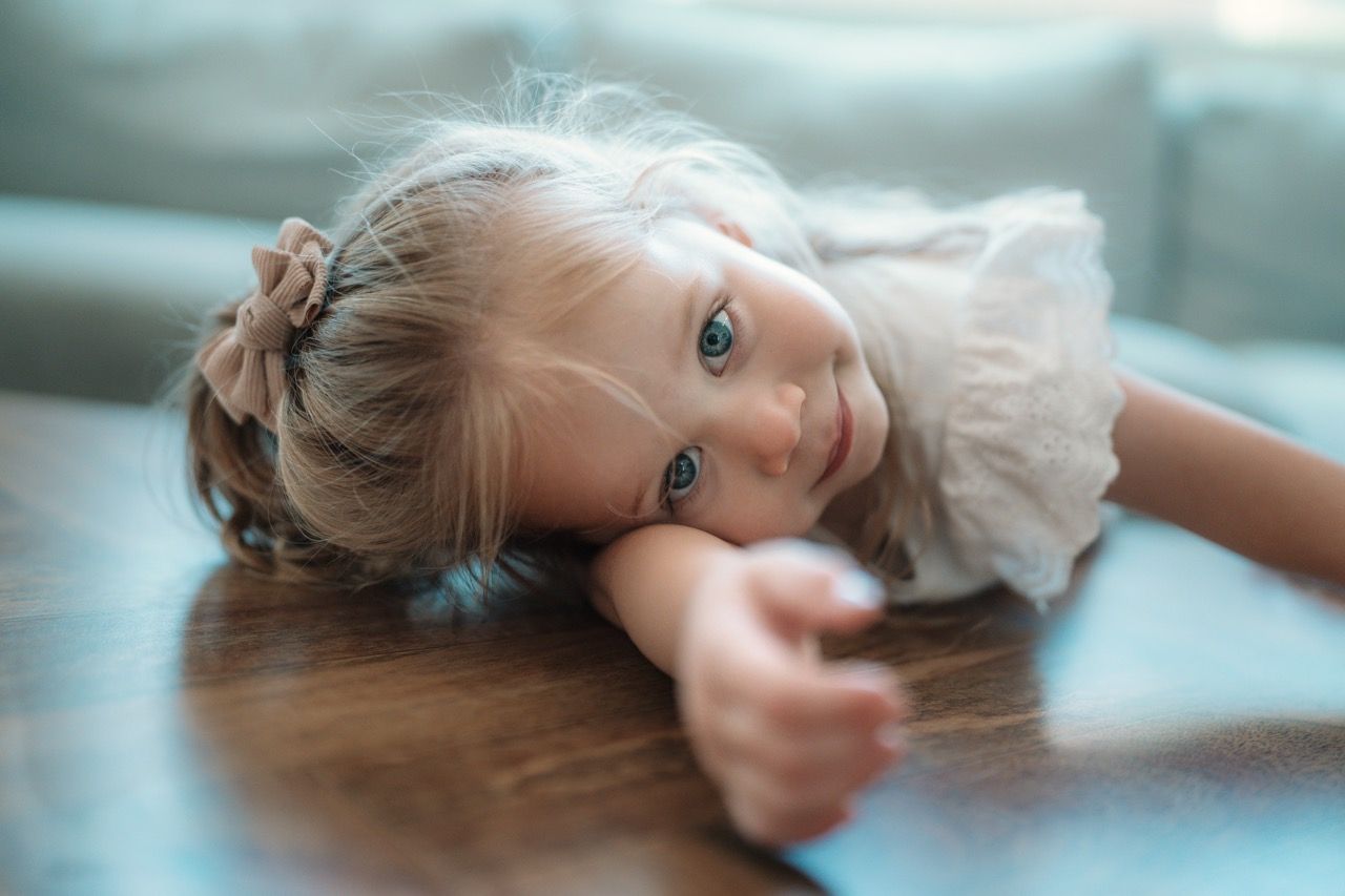 Person lying on a reflective floor in soft, dreamy lighting.