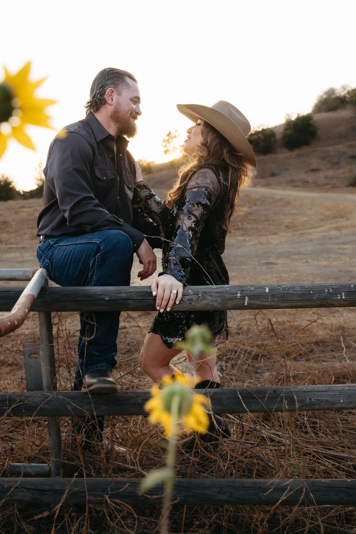 Warm cinematic portrait of a couple embracing in tall grass rolling hills at sunset in the country by Vince Shewmaker.
