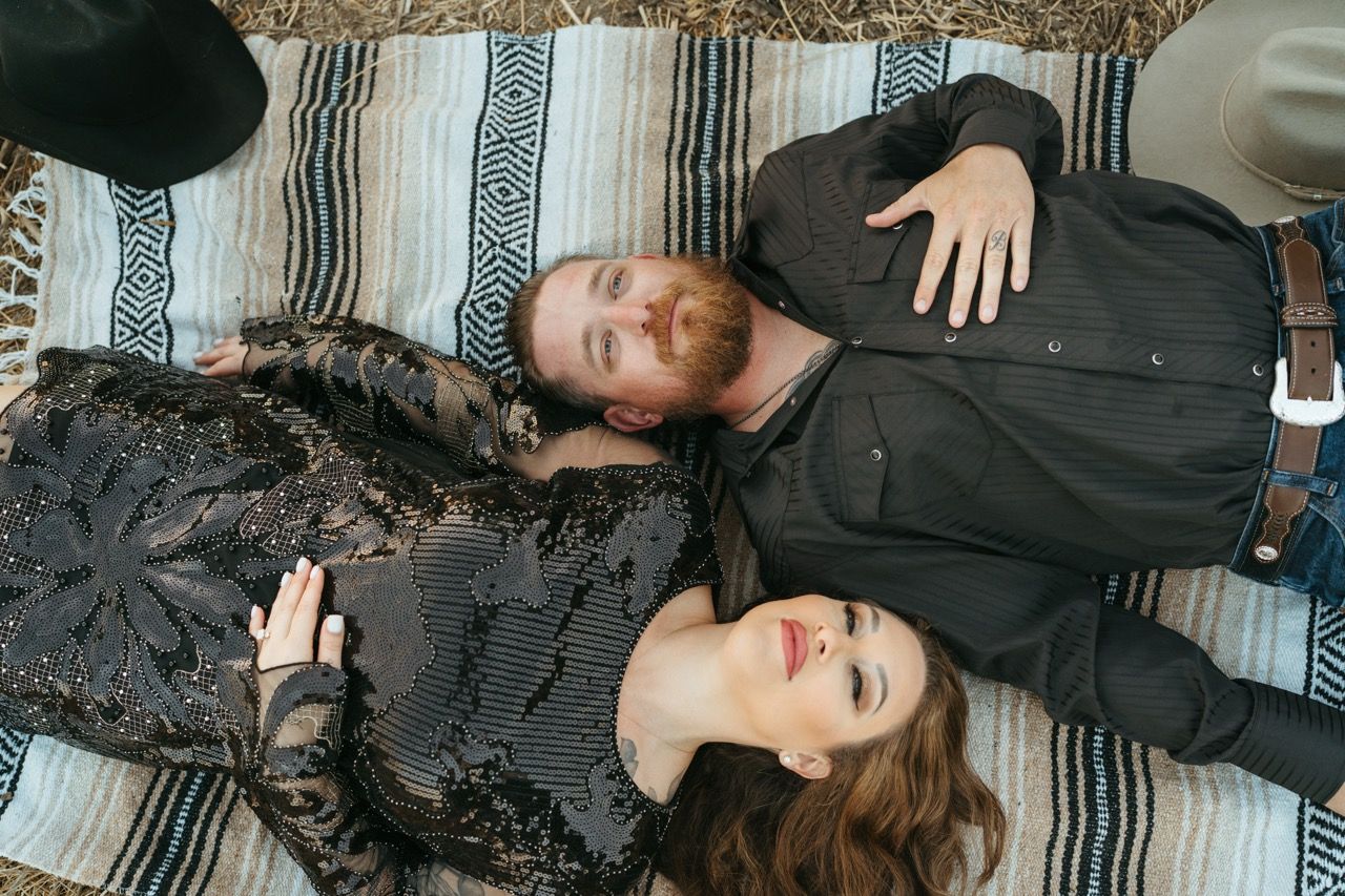 People relaxing on a striped blanket wearing dark clothing in an artistic arrangement.
