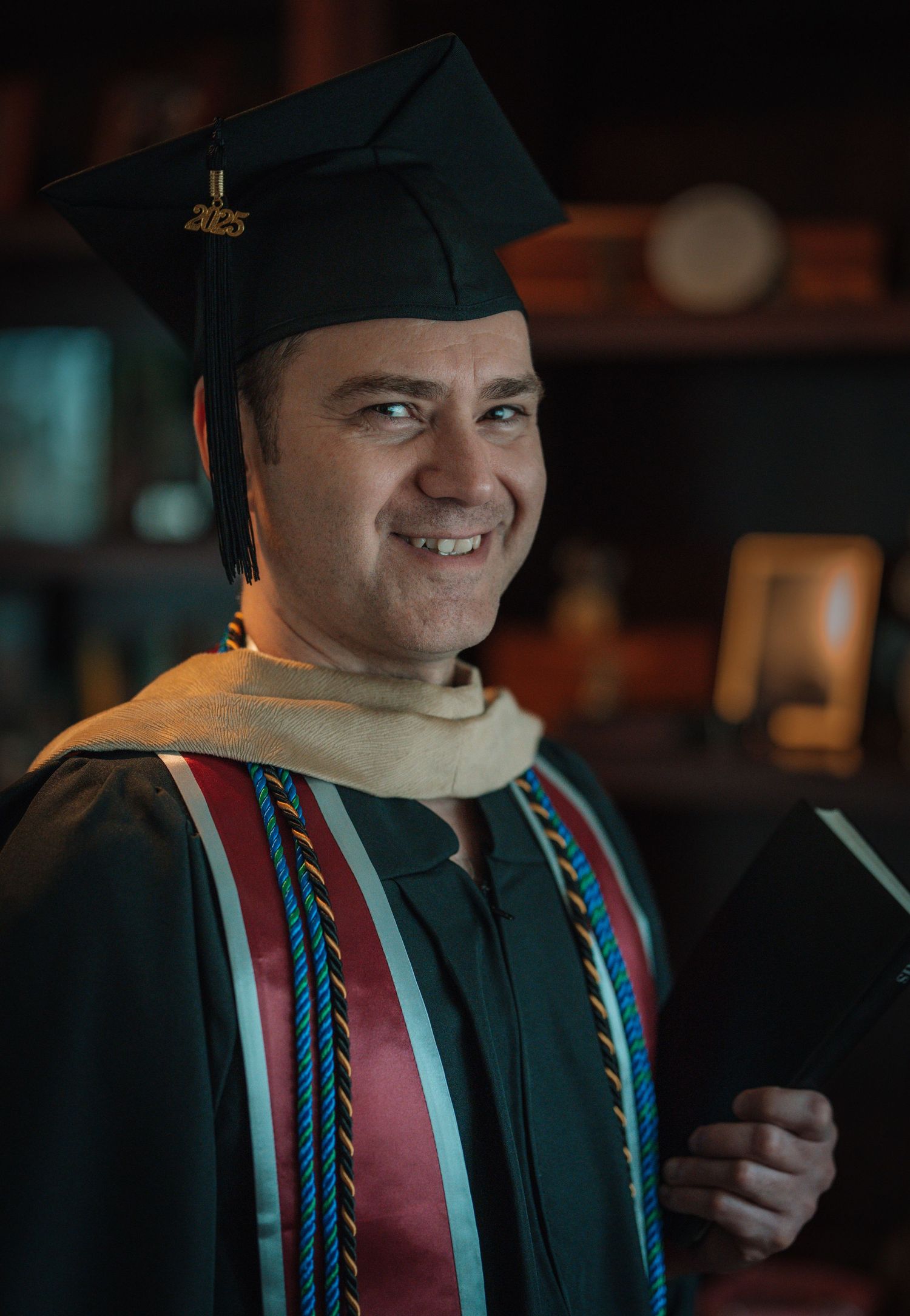 Graduate in academic regalia shown in sequence of expressive poses against dark background.