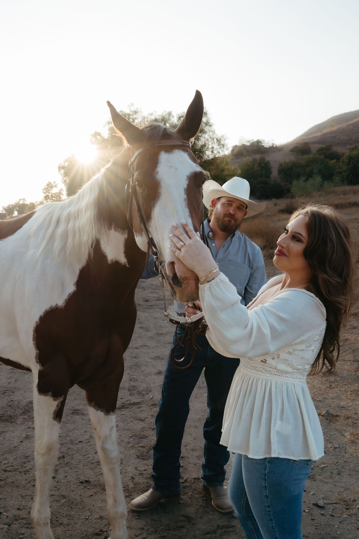 Warm cinematic portrait of a couple embracing in tall grass rolling hills at sunset in the country by Vince Shewmaker.