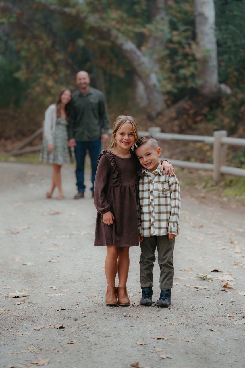 Children walking together on a leaf-covered path during autumn.