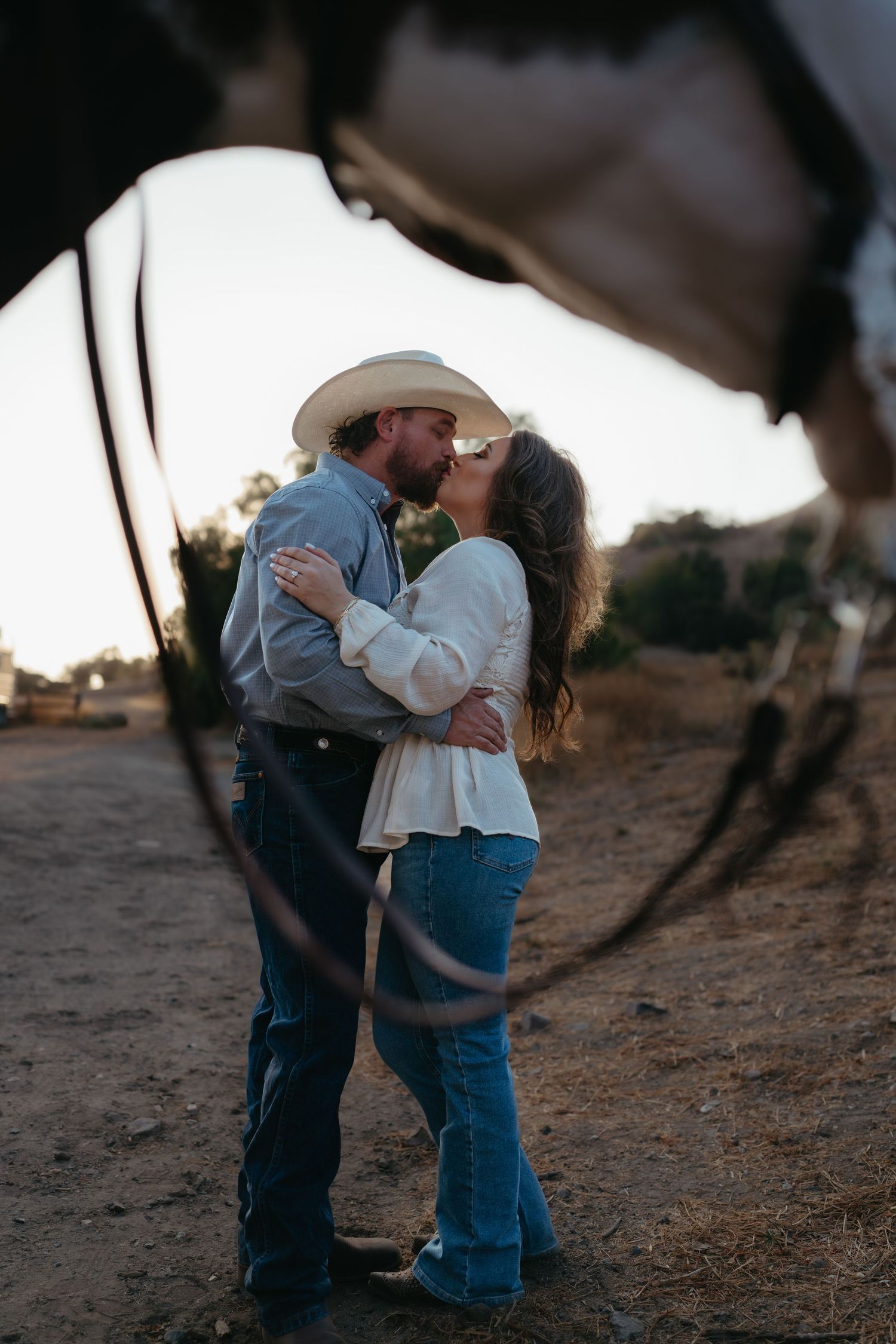 Warm cinematic portrait of a couple embracing in tall grass rolling hills at sunset in the country by Vince Shewmaker.