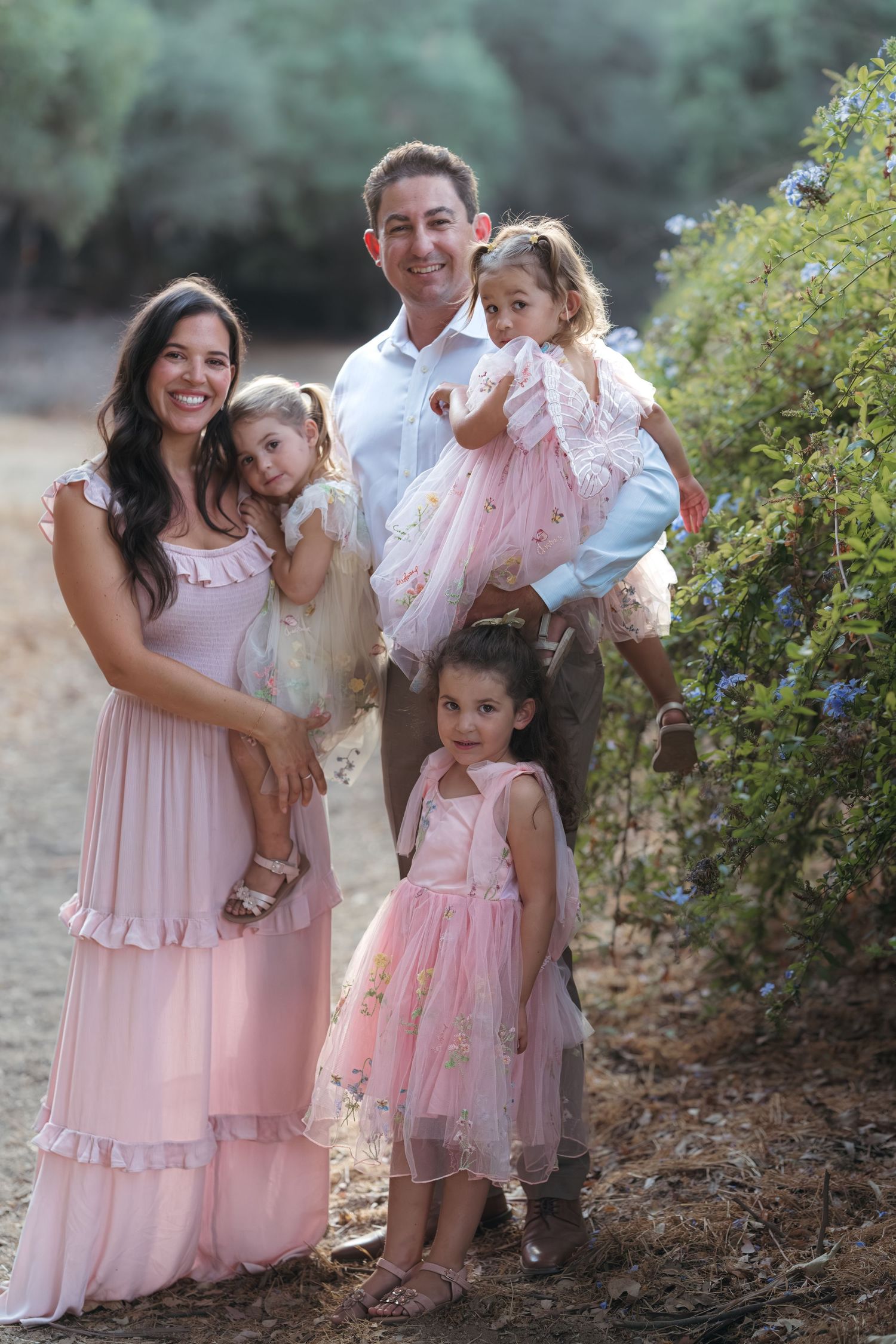 Family portrait session outdoors with everyone wearing coordinated pink outfits.