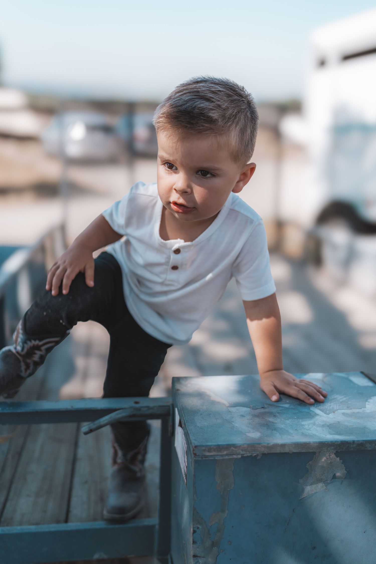 Candid environmental portrait of a young child playing in a natural outdoor setting with soft lighting by Vince Shewmaker.