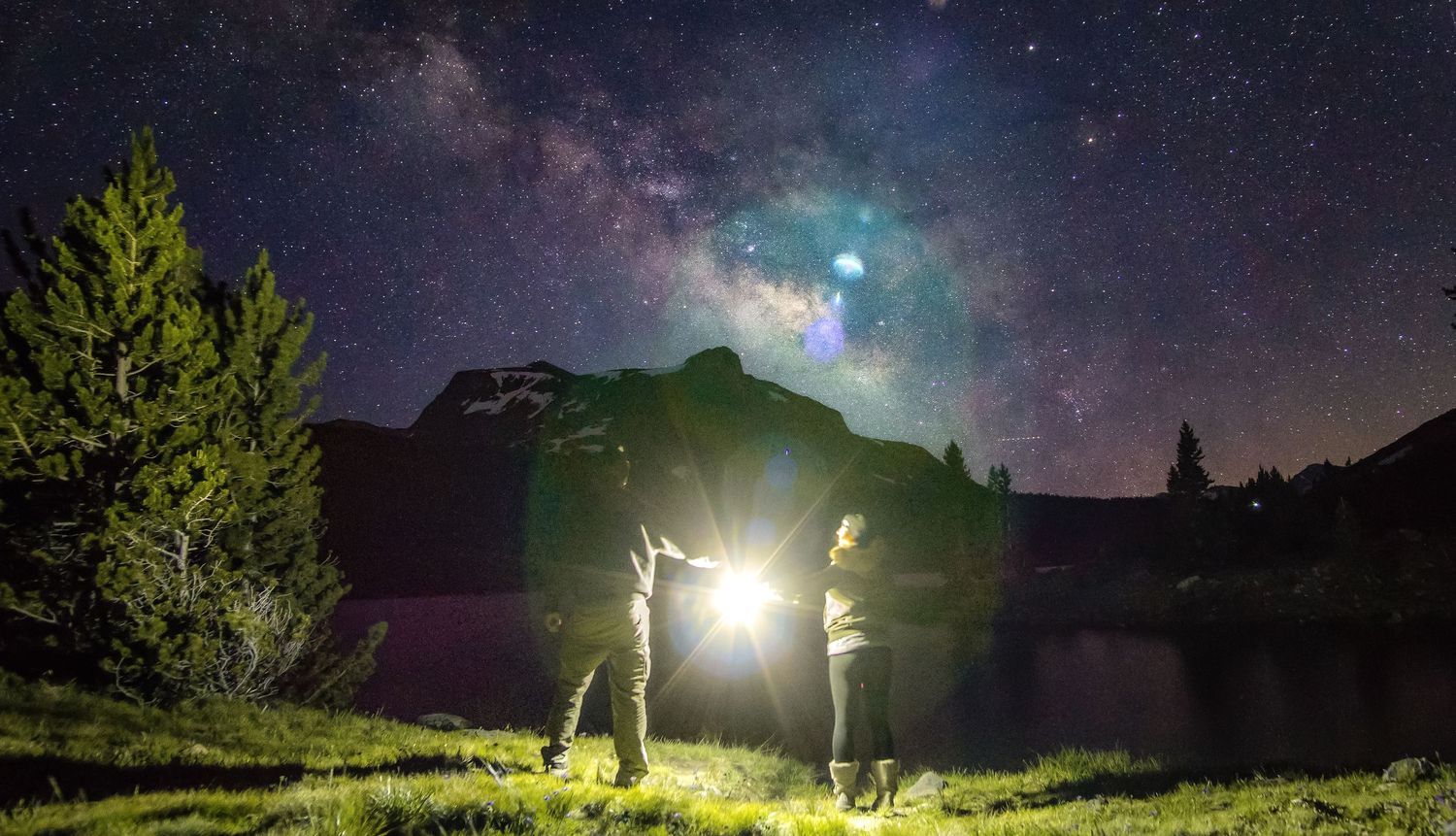 Dramatic wide-angle nature photograph of majestic mountains and stars under a moody sky by Vince Shewmaker.