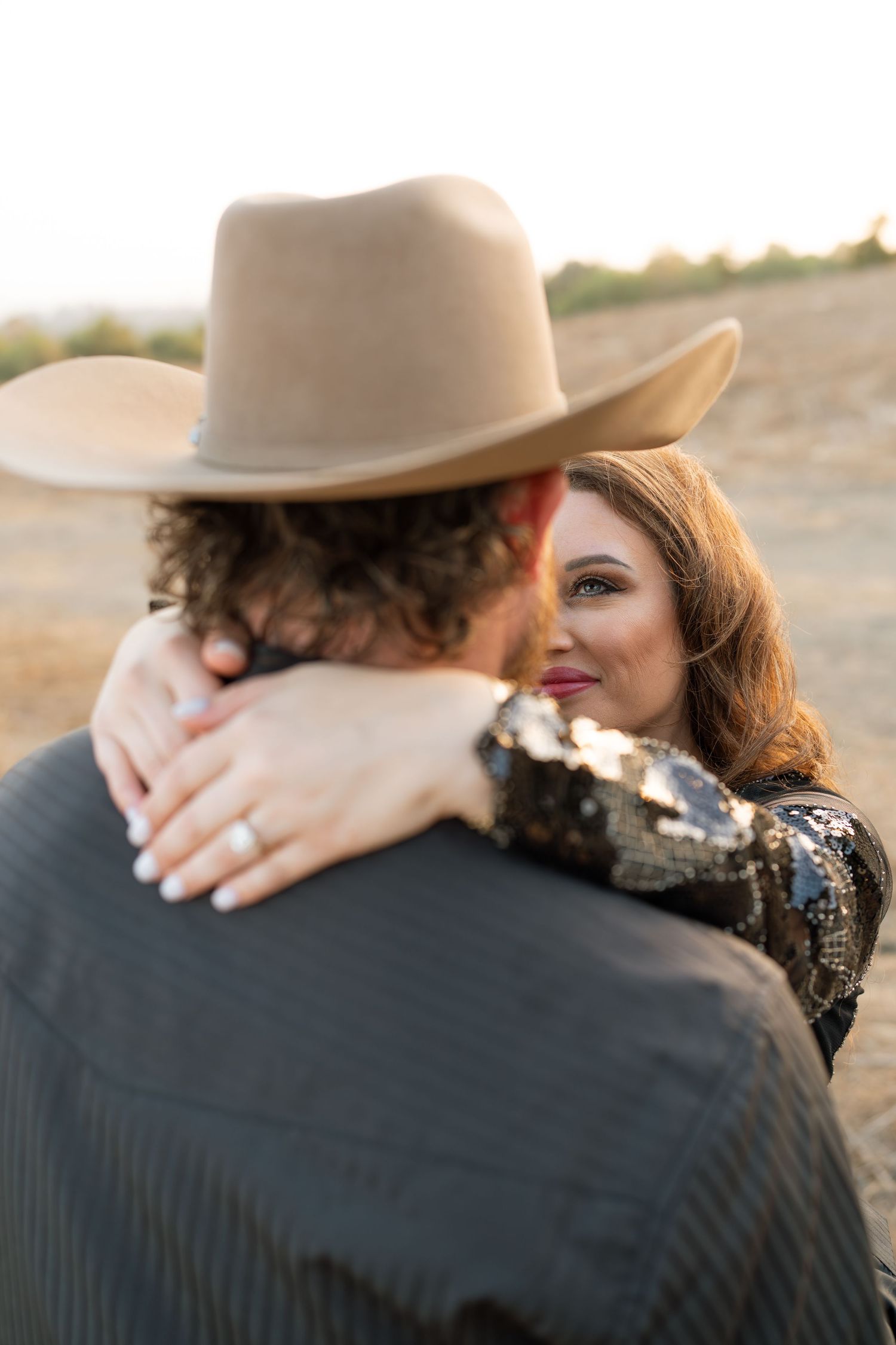 Warm cinematic portrait of a couple embracing in tall grass rolling hills at sunset in the country by Vince Shewmaker.