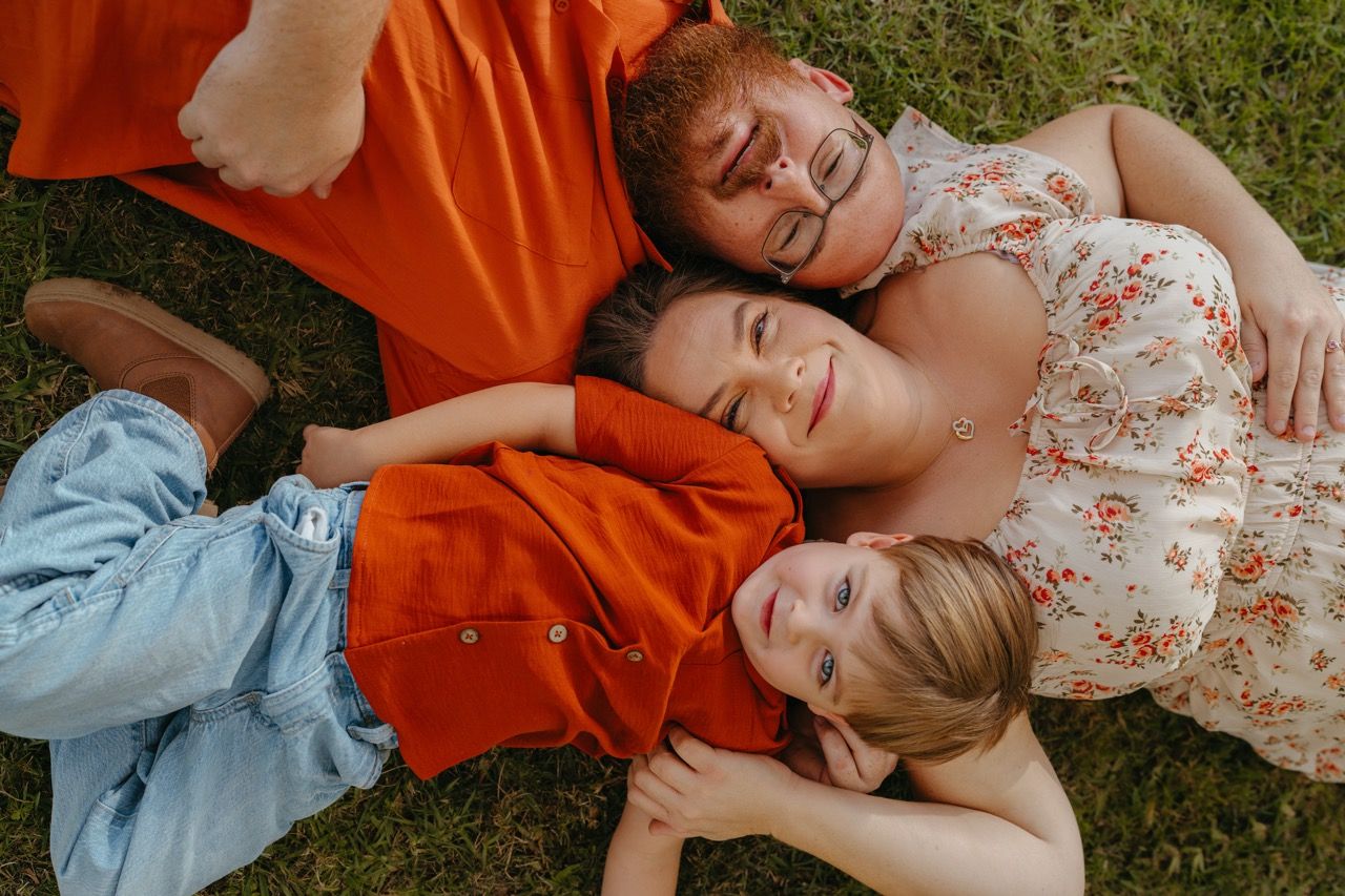 People lying on orange blankets in grass during an outdoor photo session.