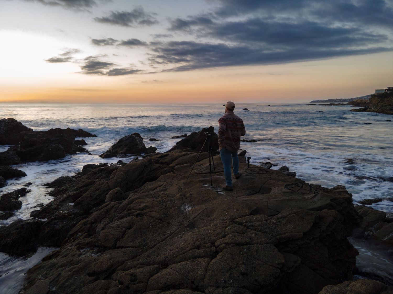Cinematic landscape photograph of a dramatic sunset over the rocky cliffs and crashing waves of Laguna Beach California by Vince Shewmaker.
